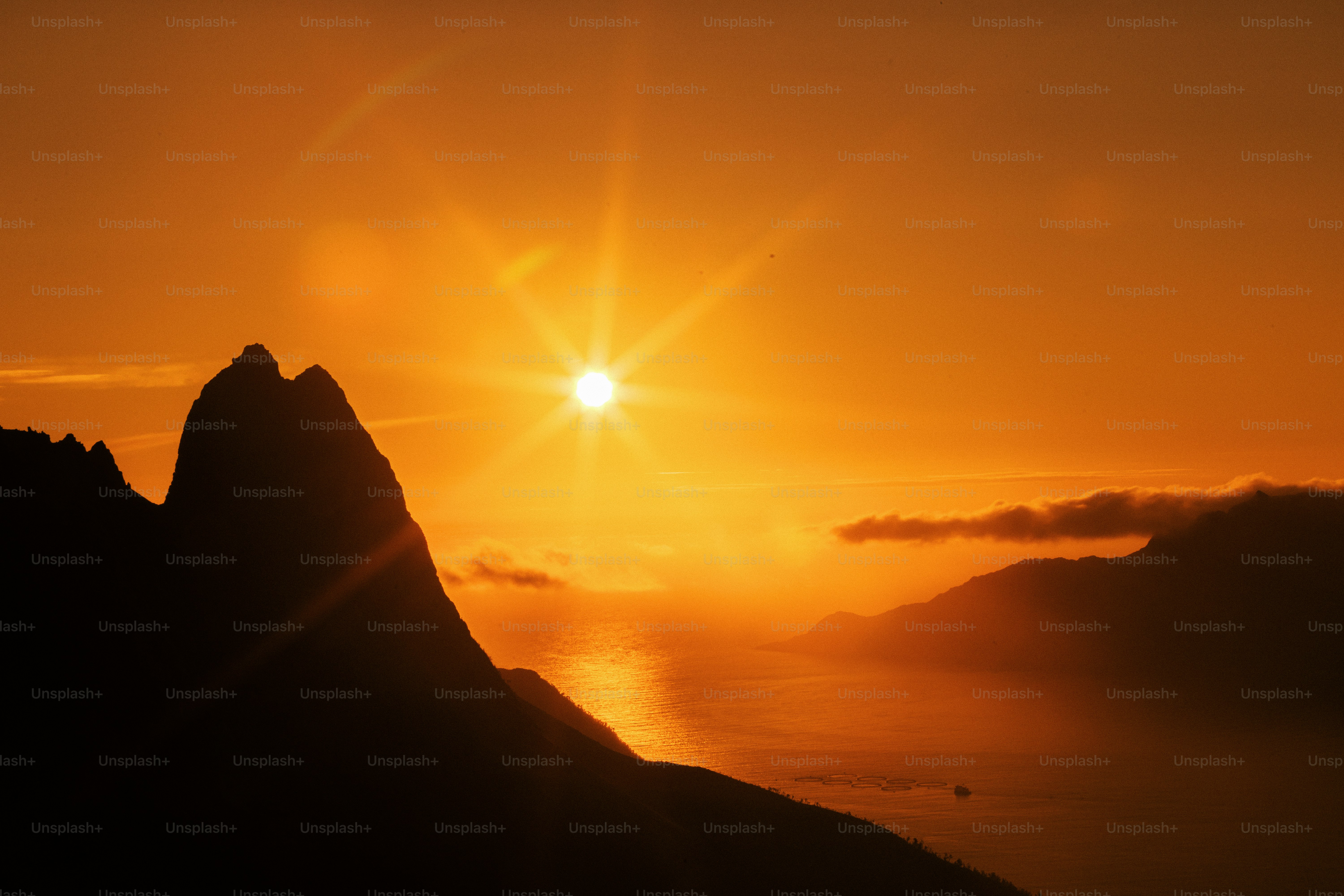 Fiery sunset over ocean with mountain silhouettes
