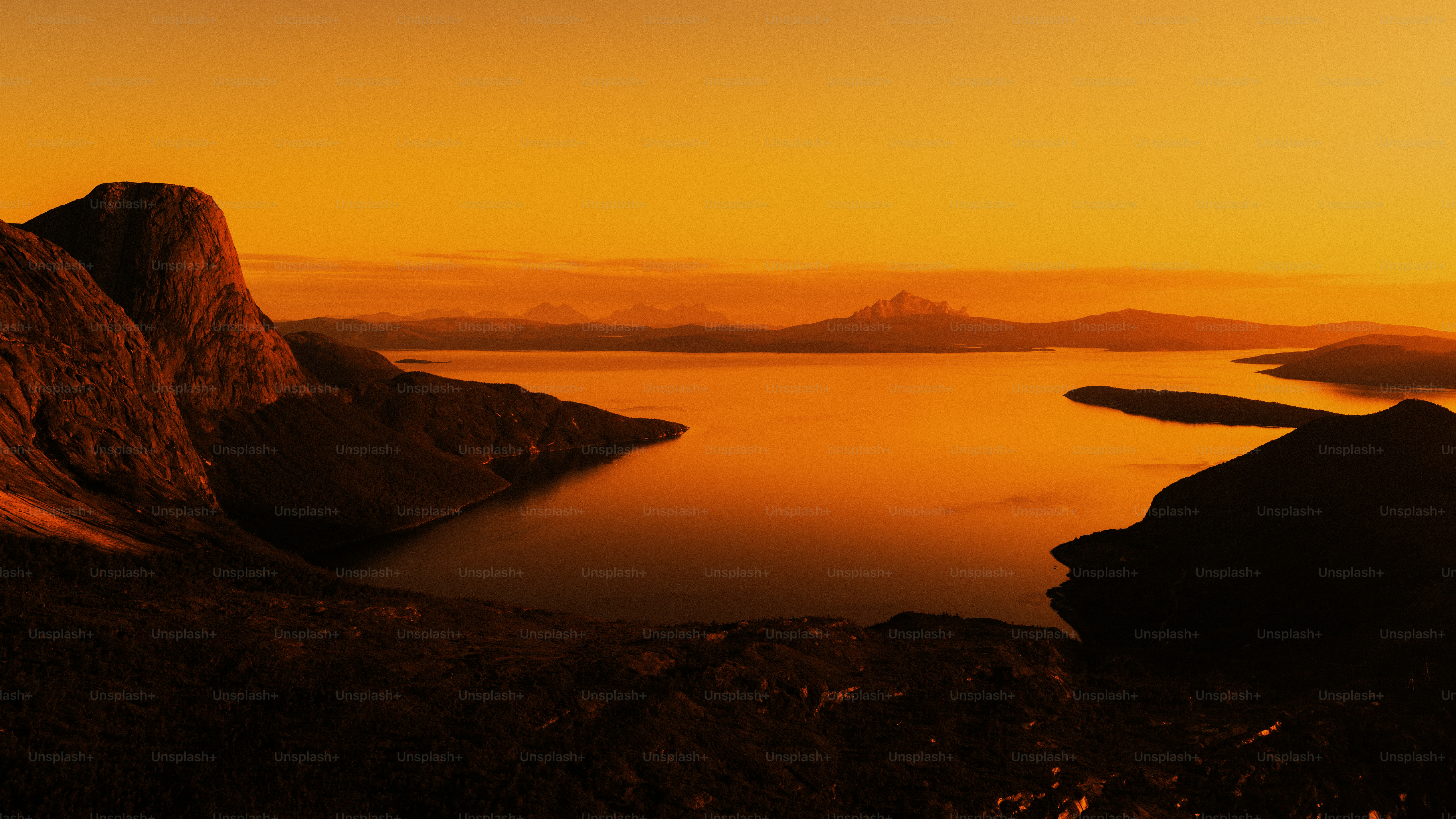 Fiery sunset over calm lake and mountains - Photo on Unsplash+