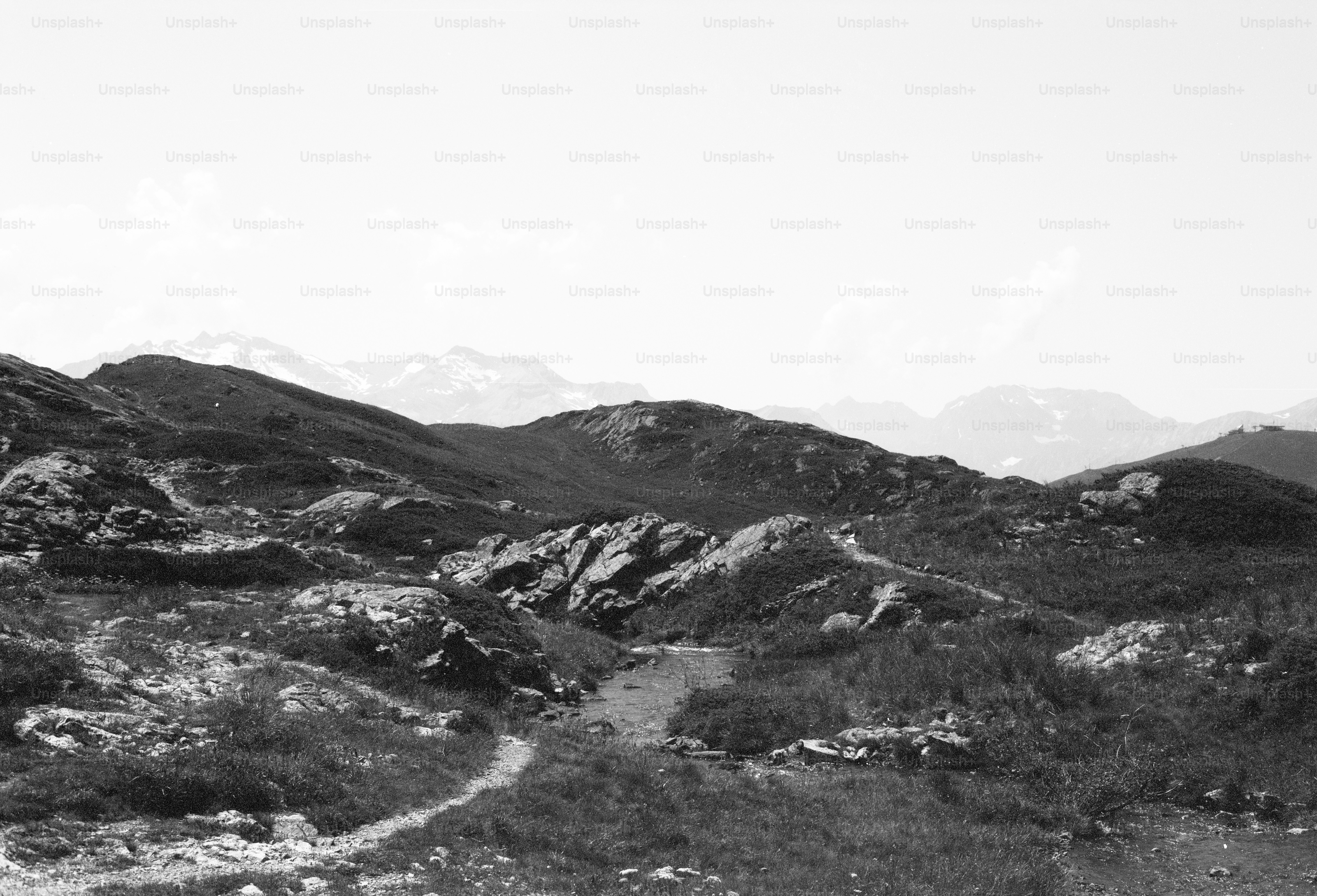 Winding path through rocky hills, distant mountains
