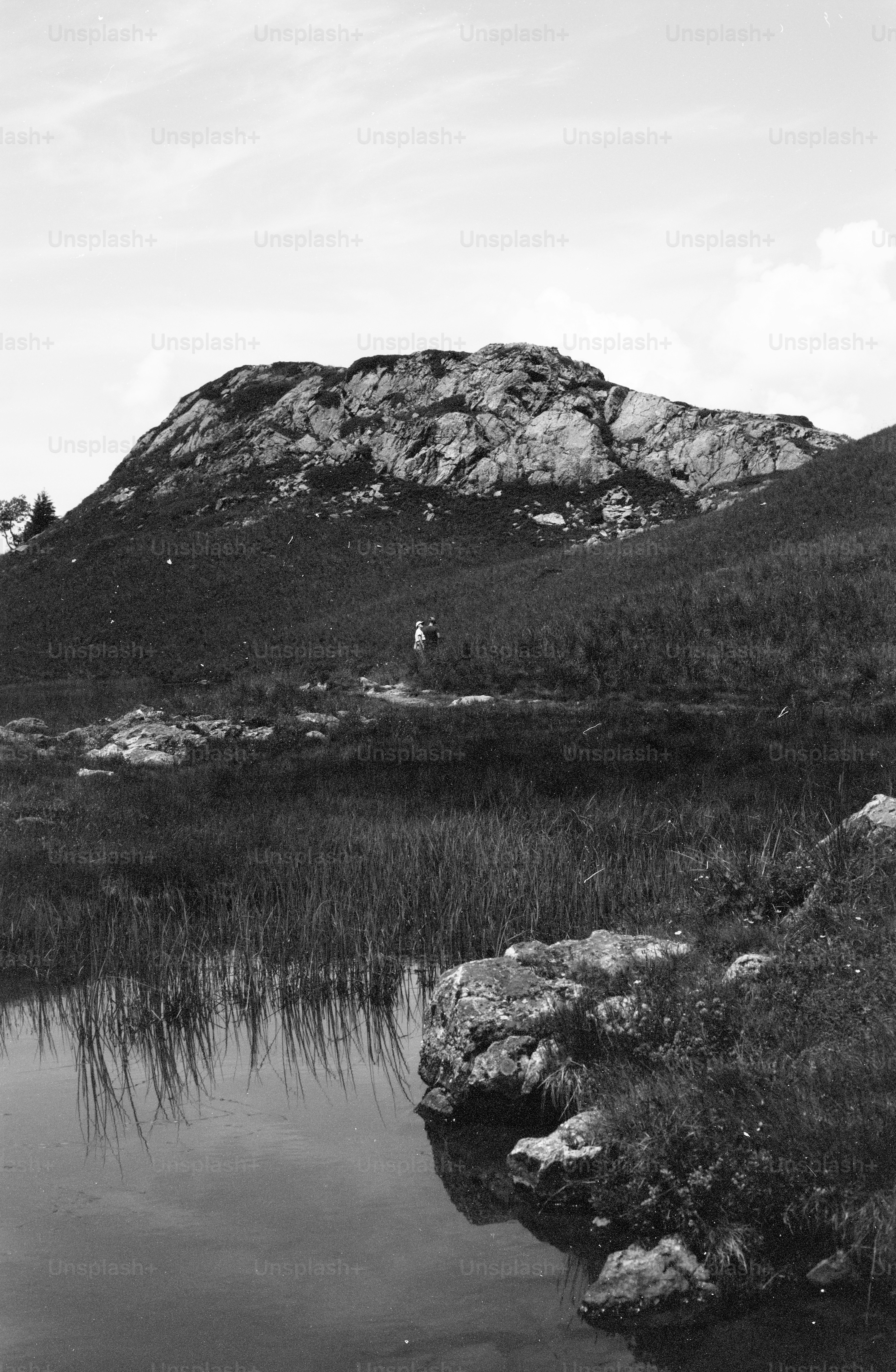 Hiker on path near rocky hill and pond