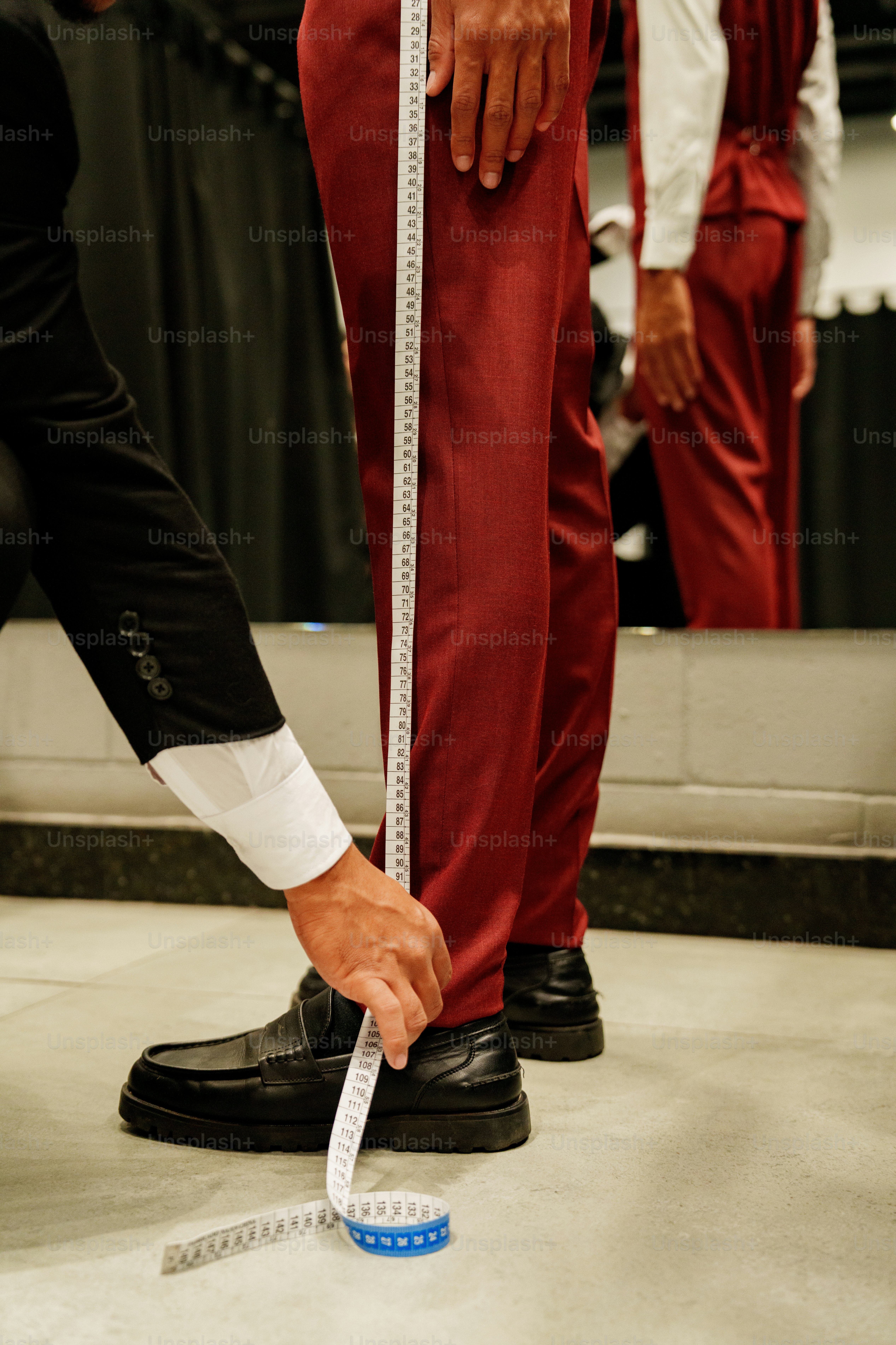 Tailor measuring man's red pants