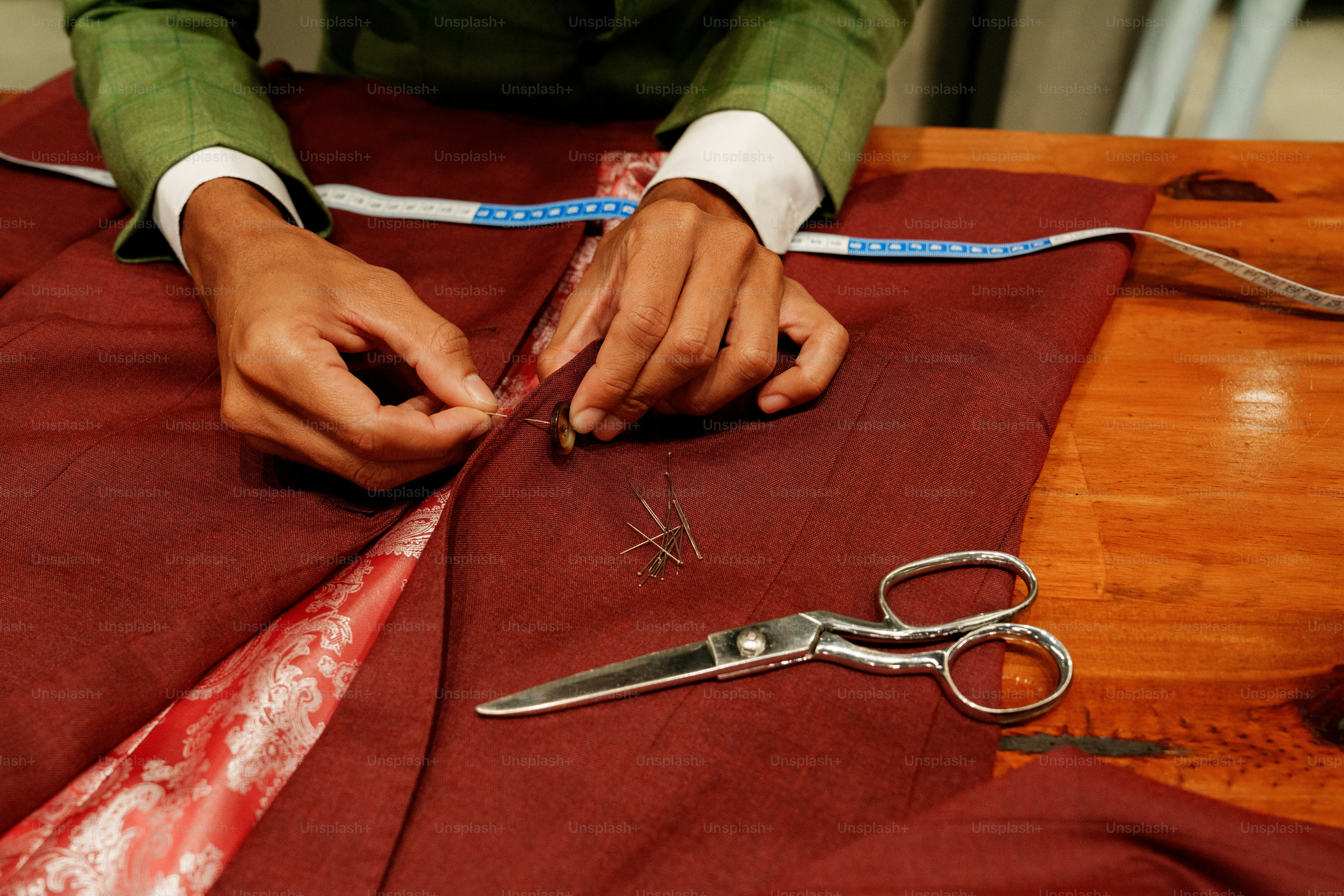 Tailor pinning red fabric with measuring tape