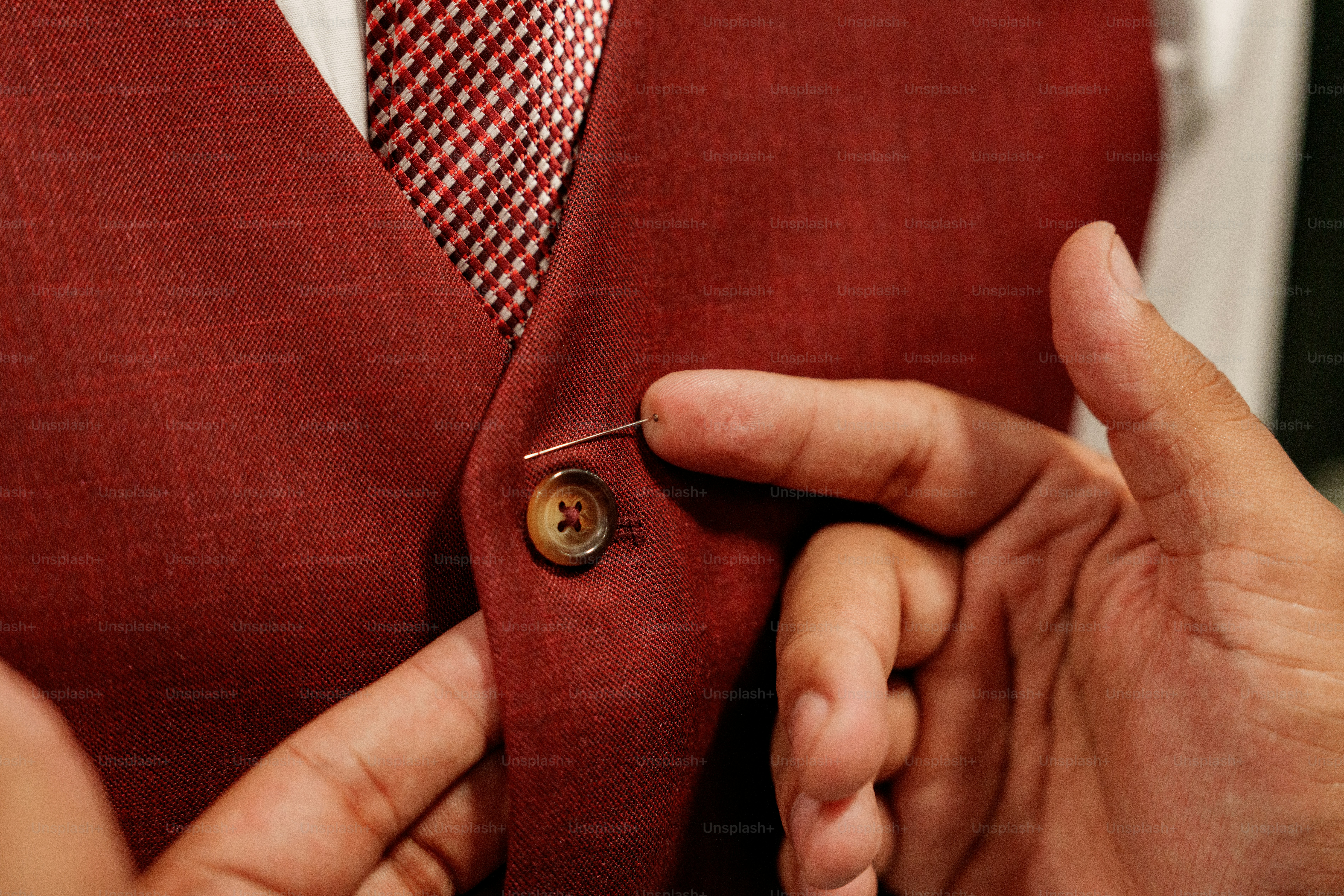 Hands adjusting red suit vest with pin