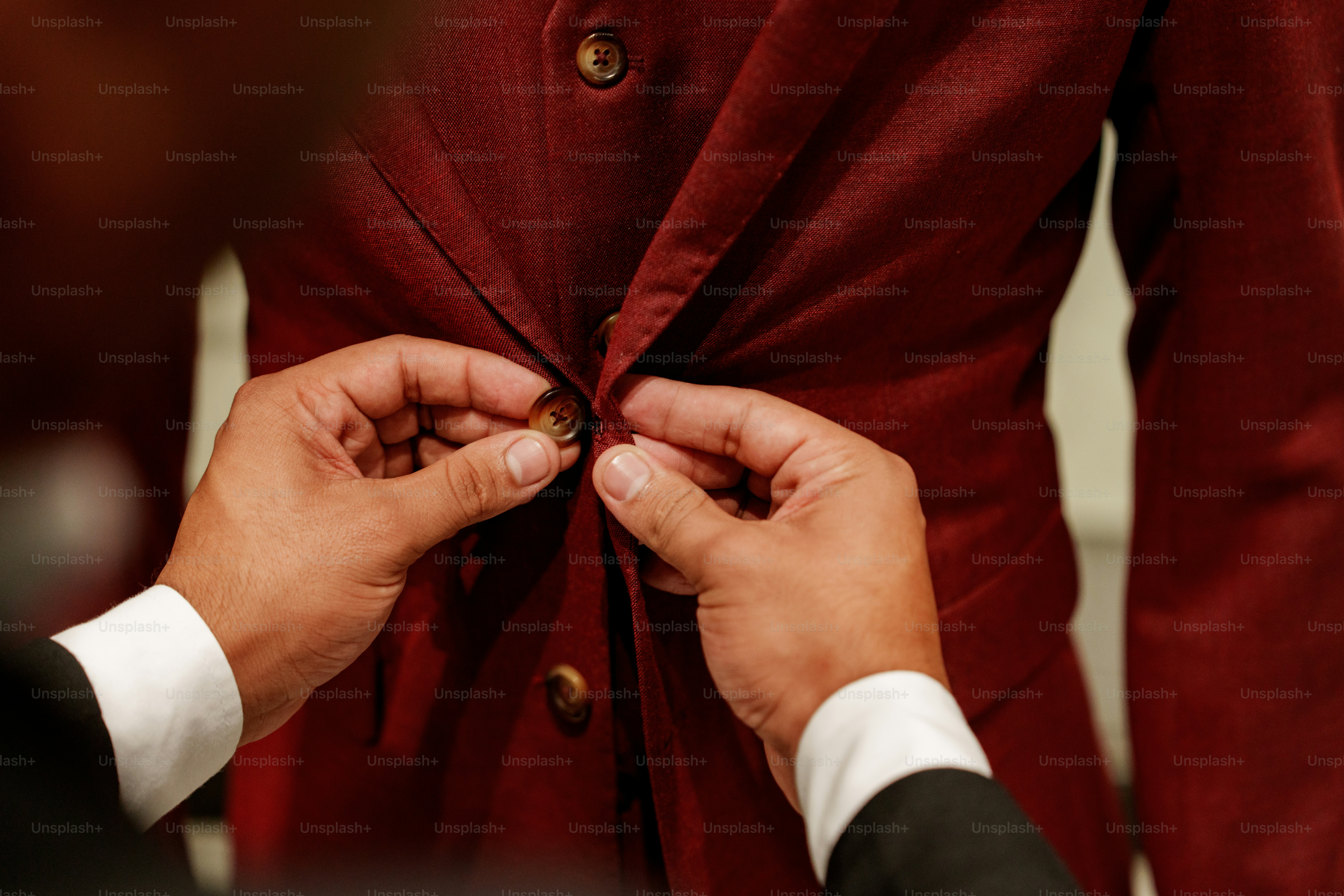 Hands fastening buttons on a red jacket
