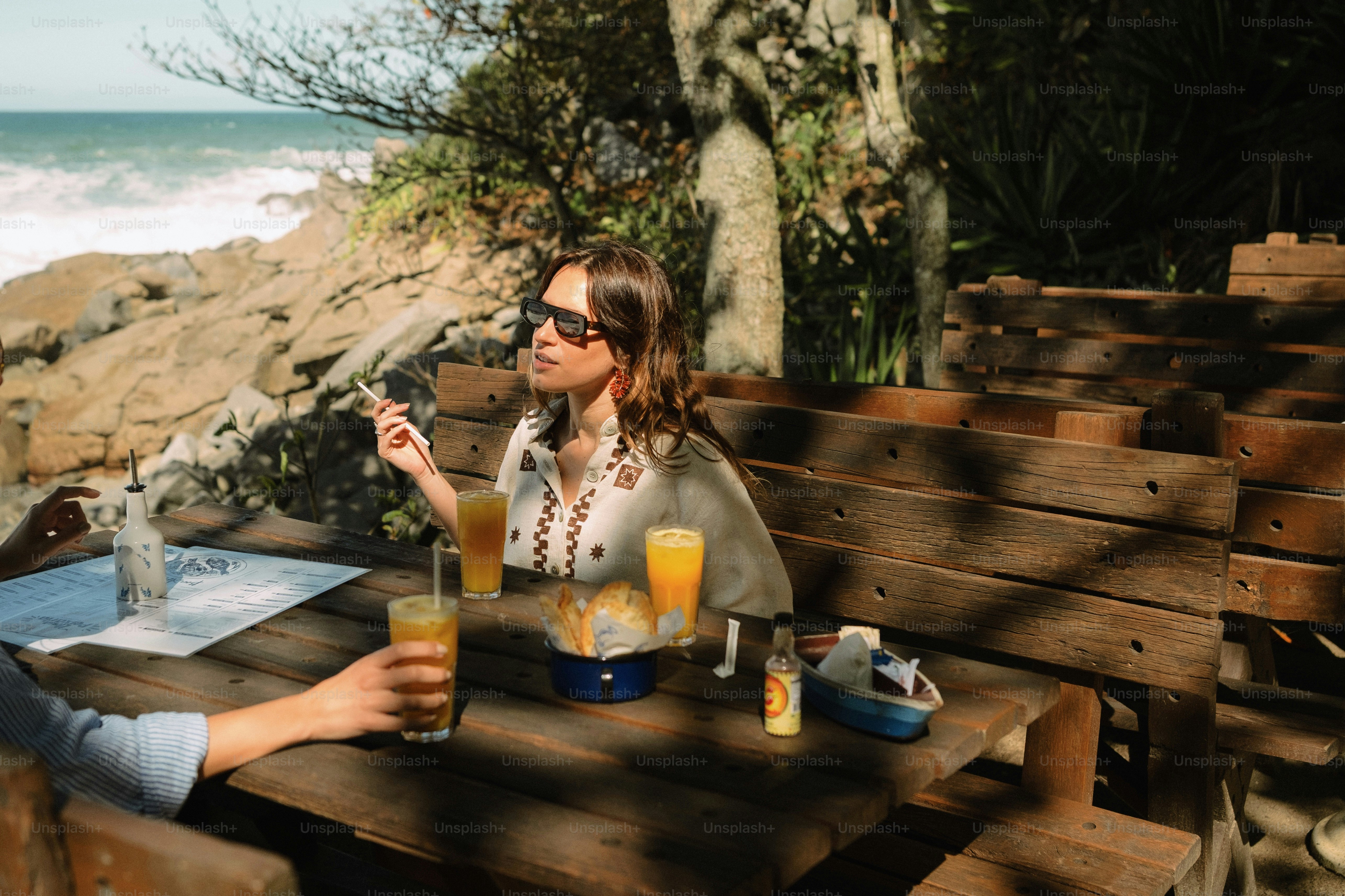 Woman in sunglasses smoking by the ocean