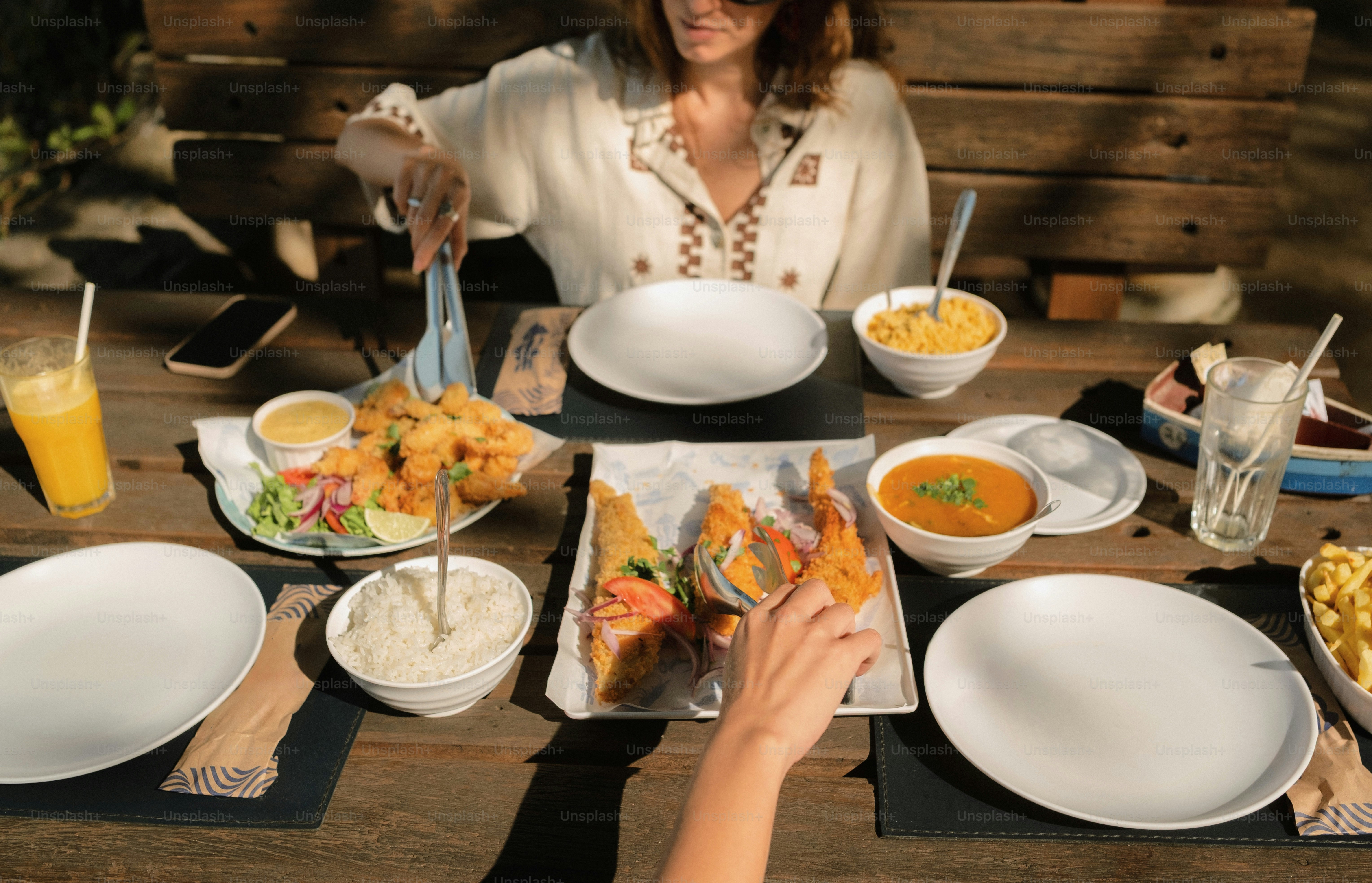 Sharing fried food, rice, and drinks on wooden table.