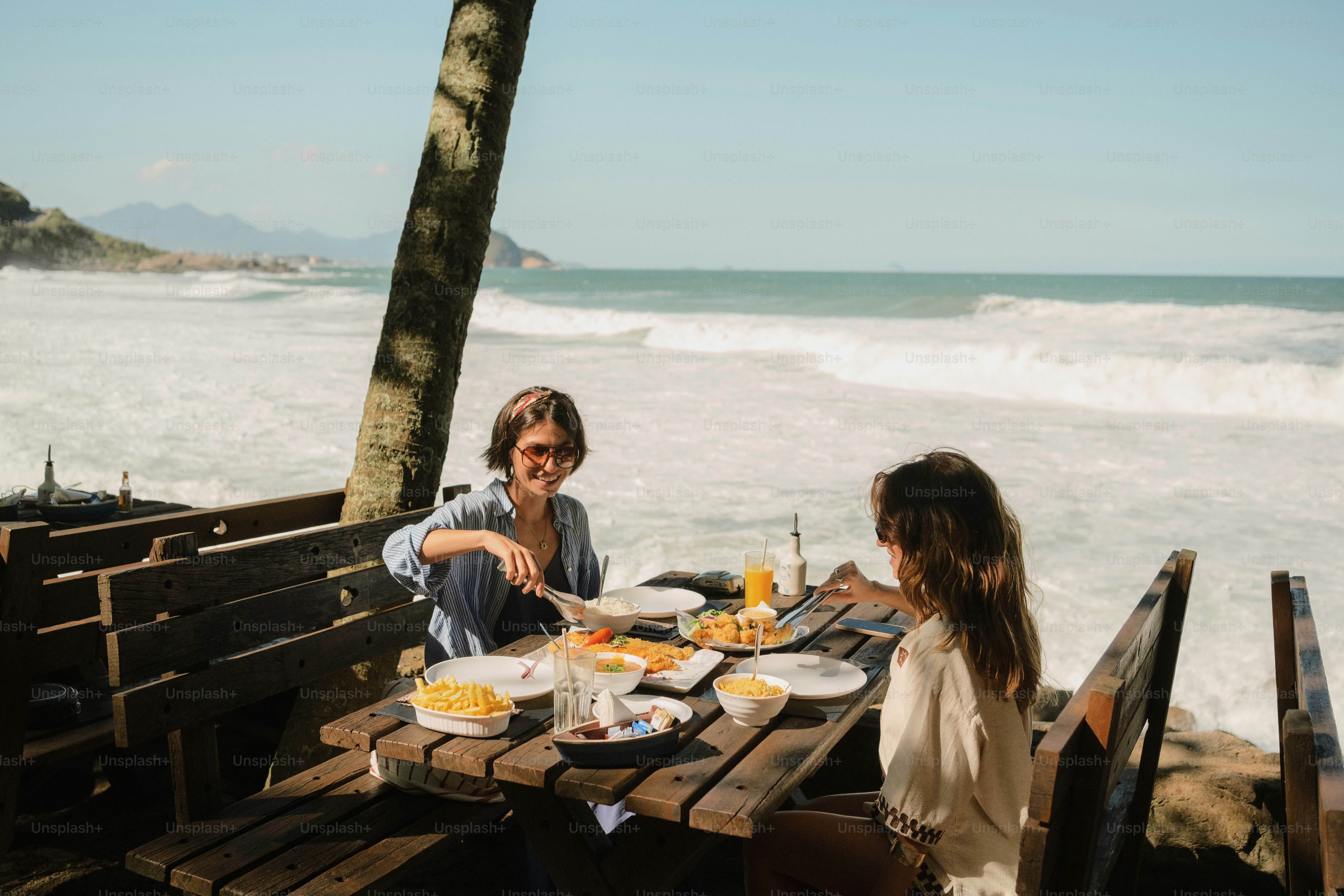 Woman and child eating by ocean waves