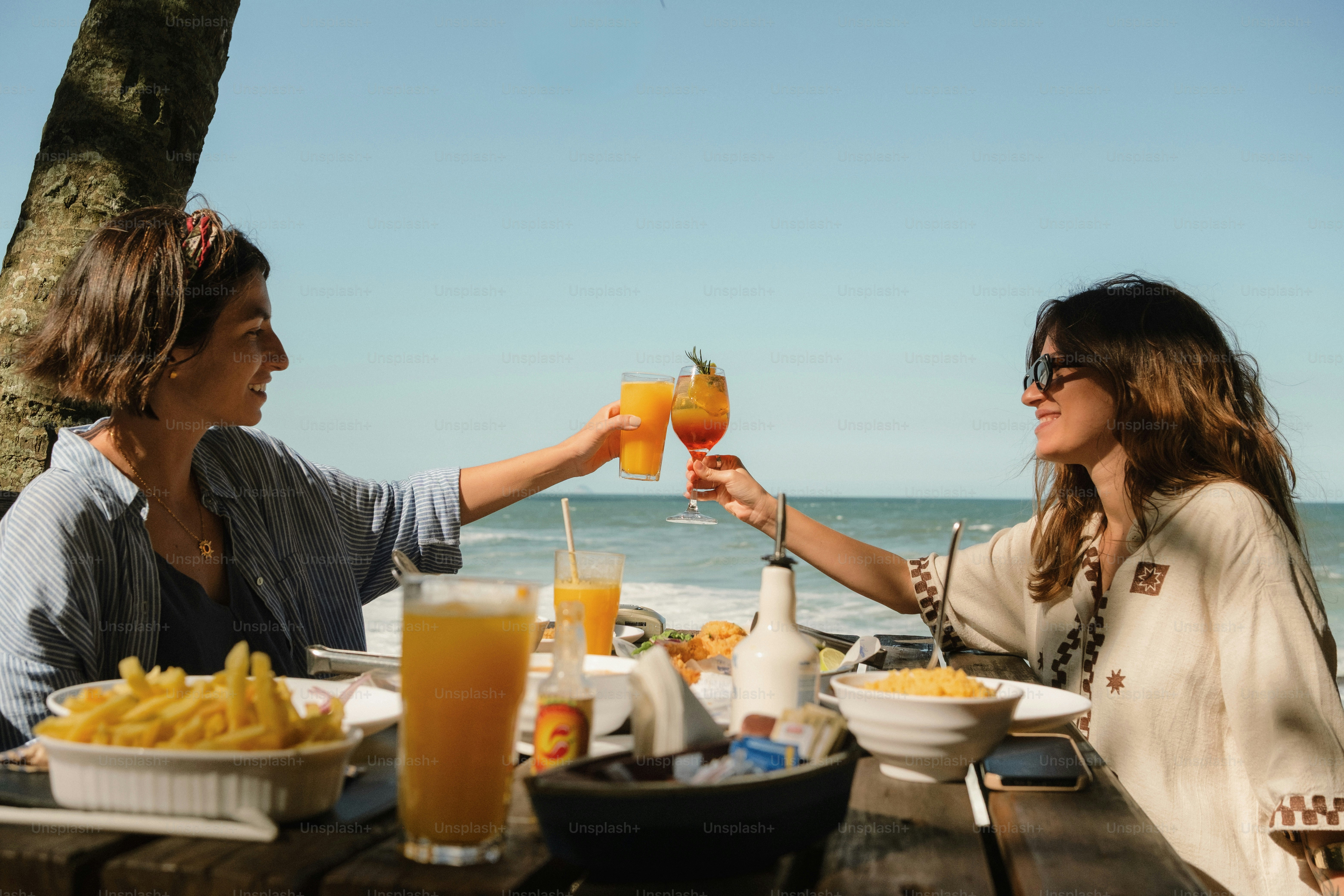 Women toasting drinks by the ocean