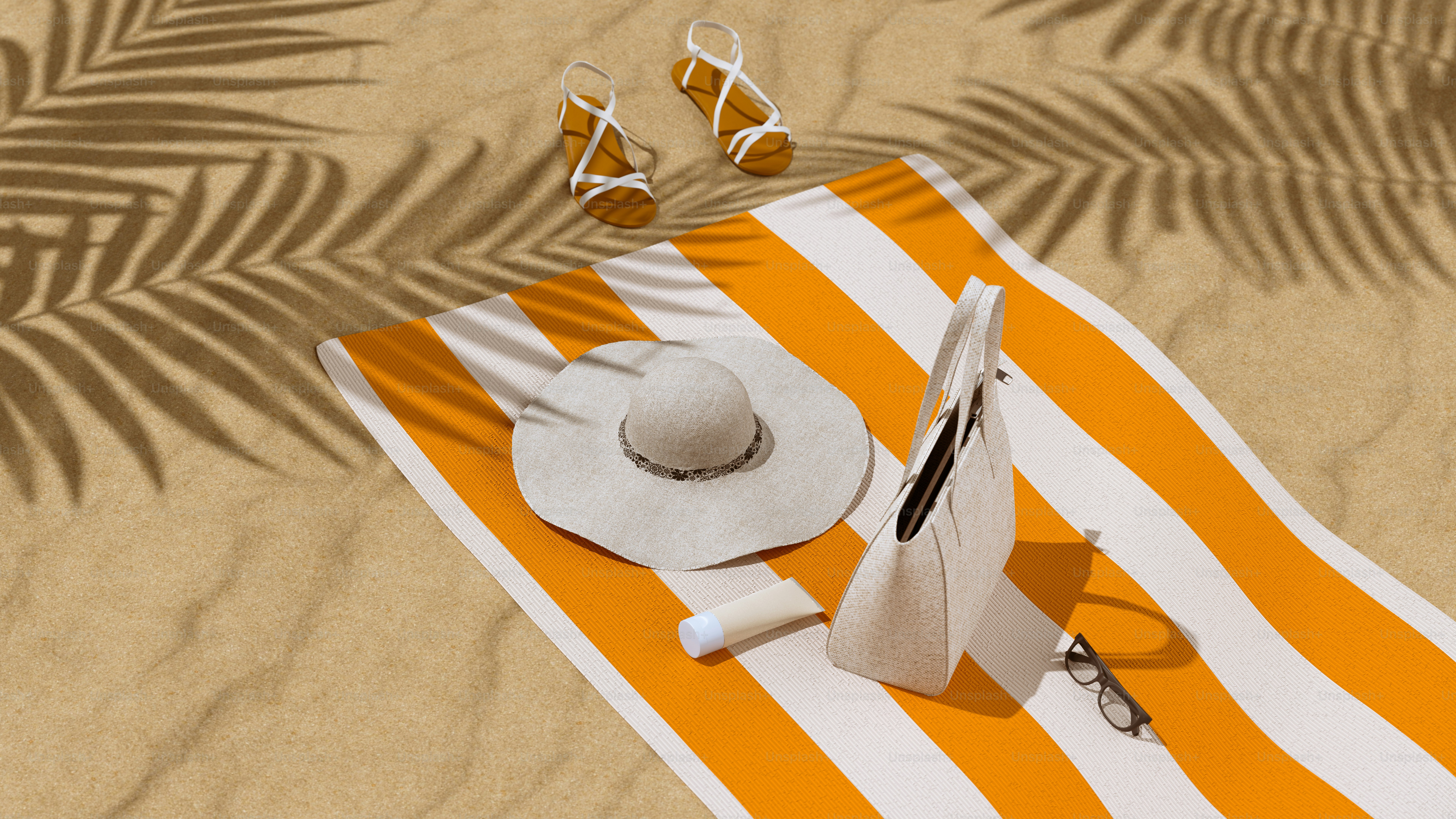 Summer beach essentials on striped towel with palm shadows