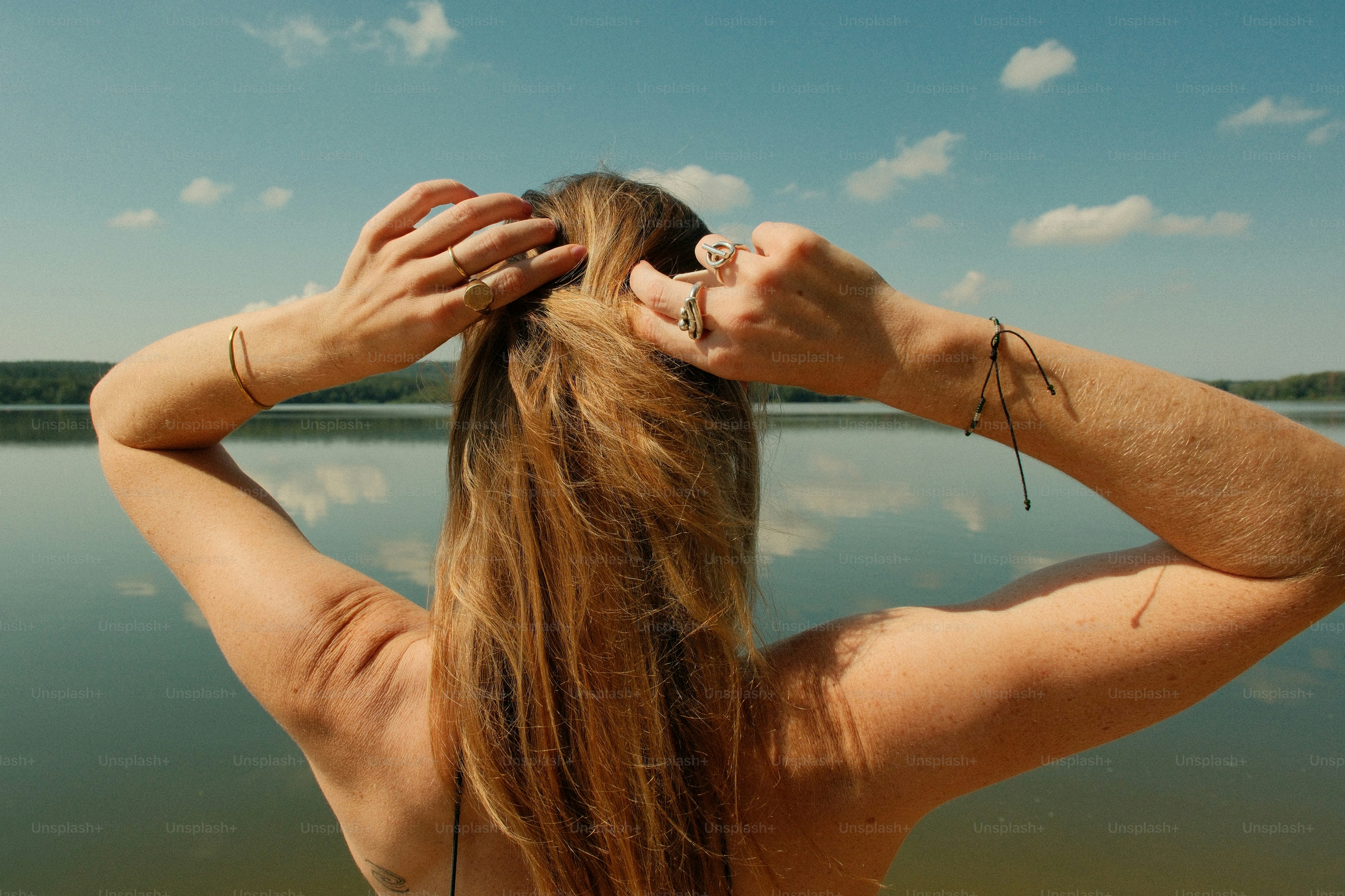 Woman adjusting hair by tranquil lake