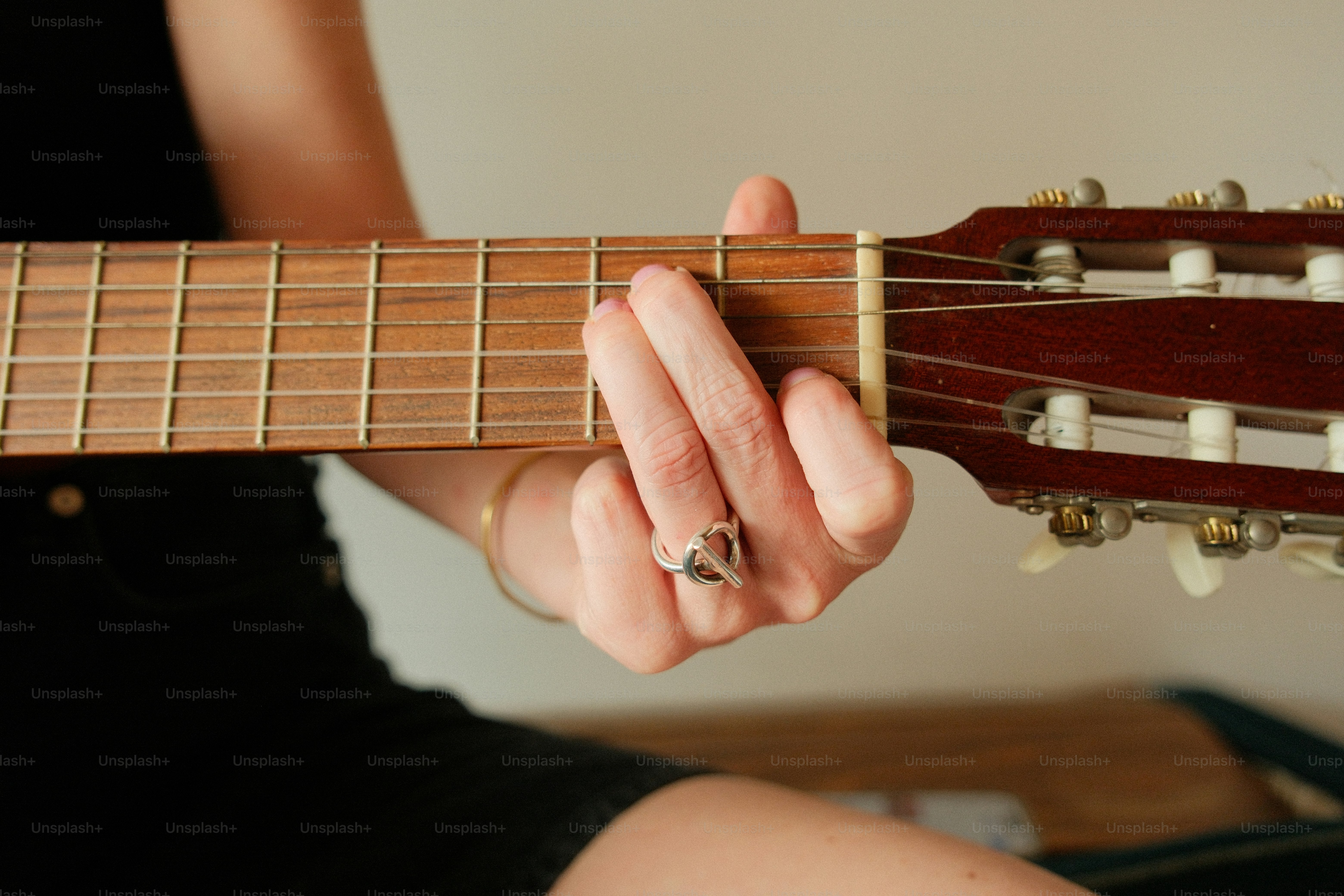 Hand playing chord on acoustic guitar fretboard