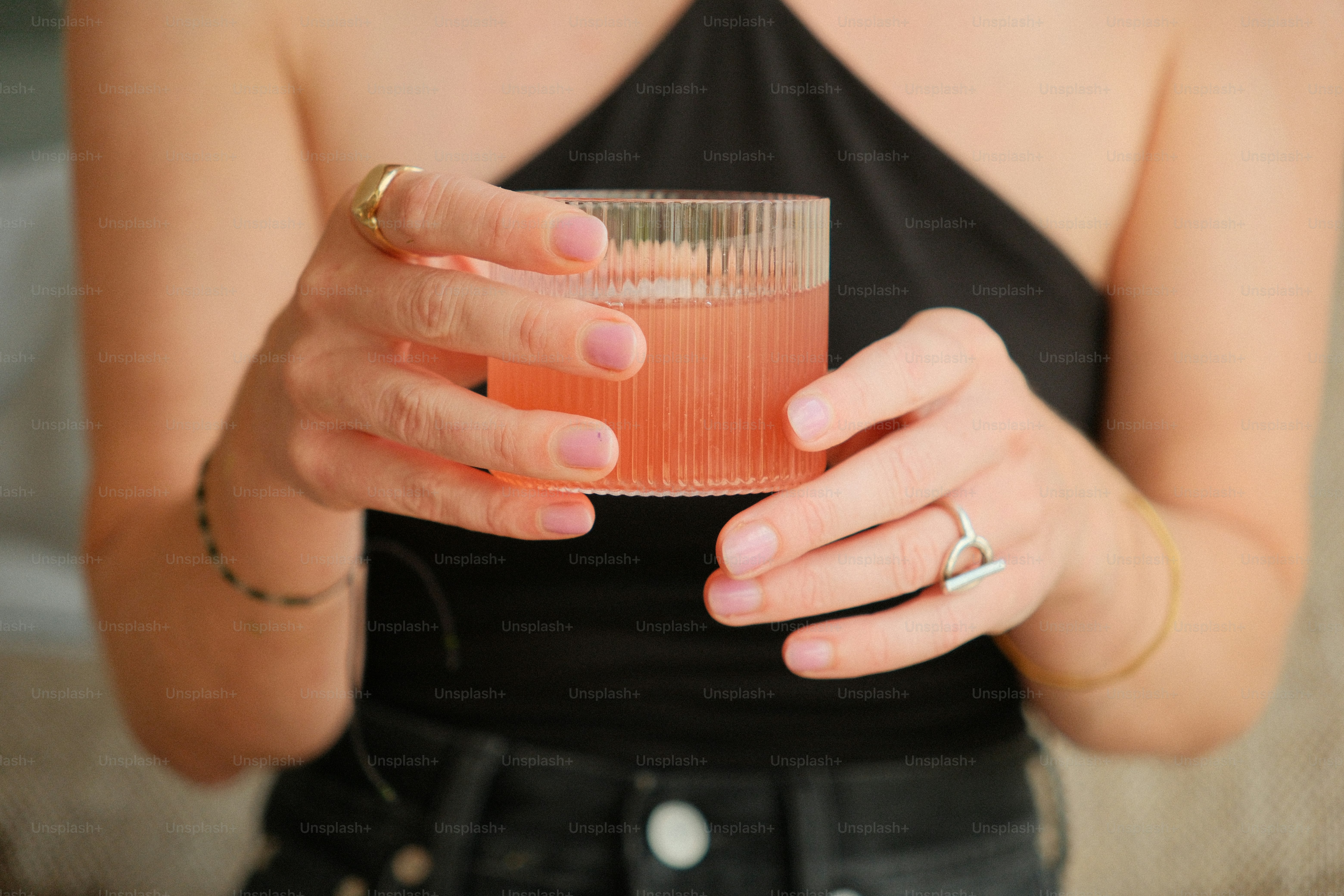 Hands holding pink drink in ribbed glass