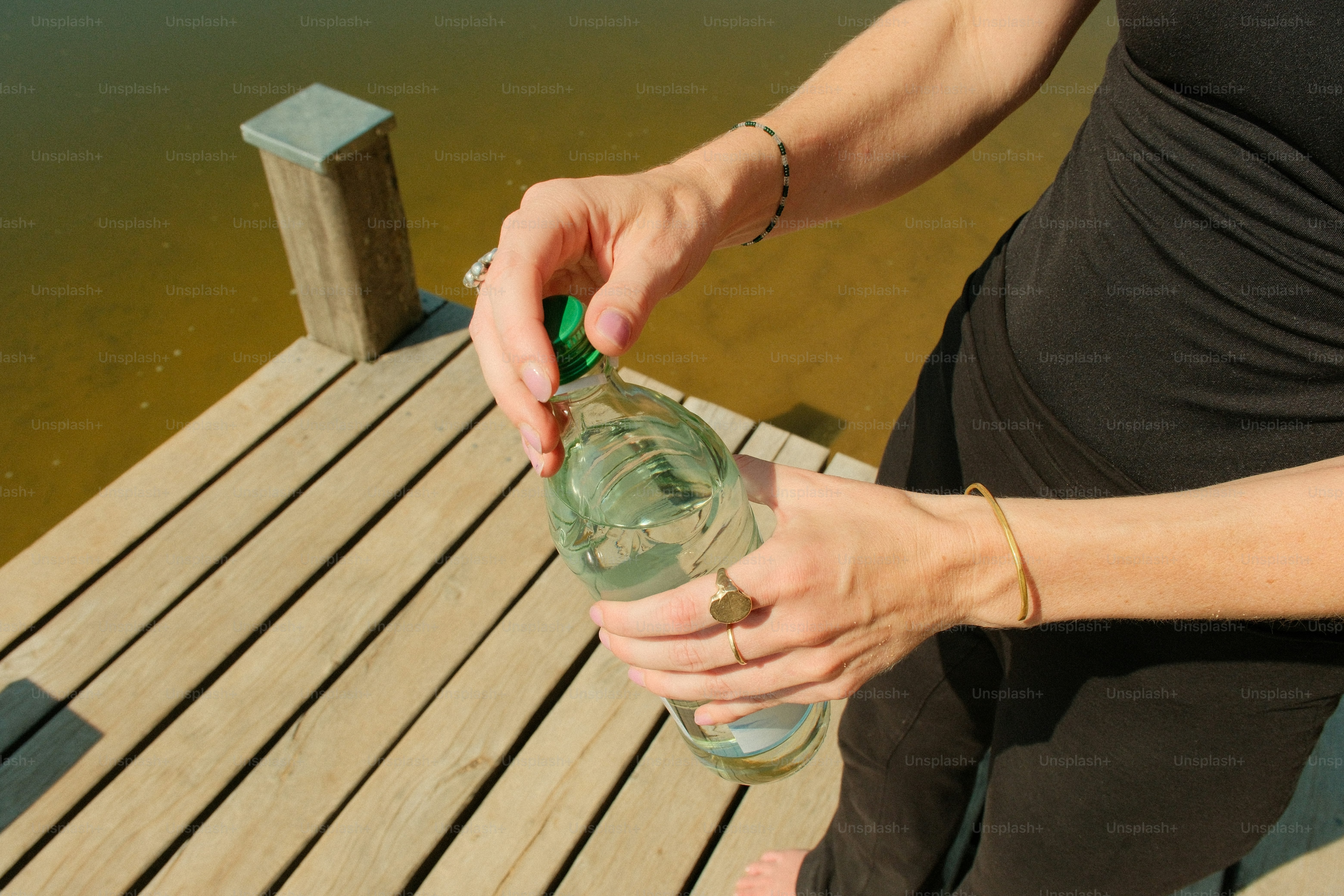 Hands opening a bottle on wooden dock
