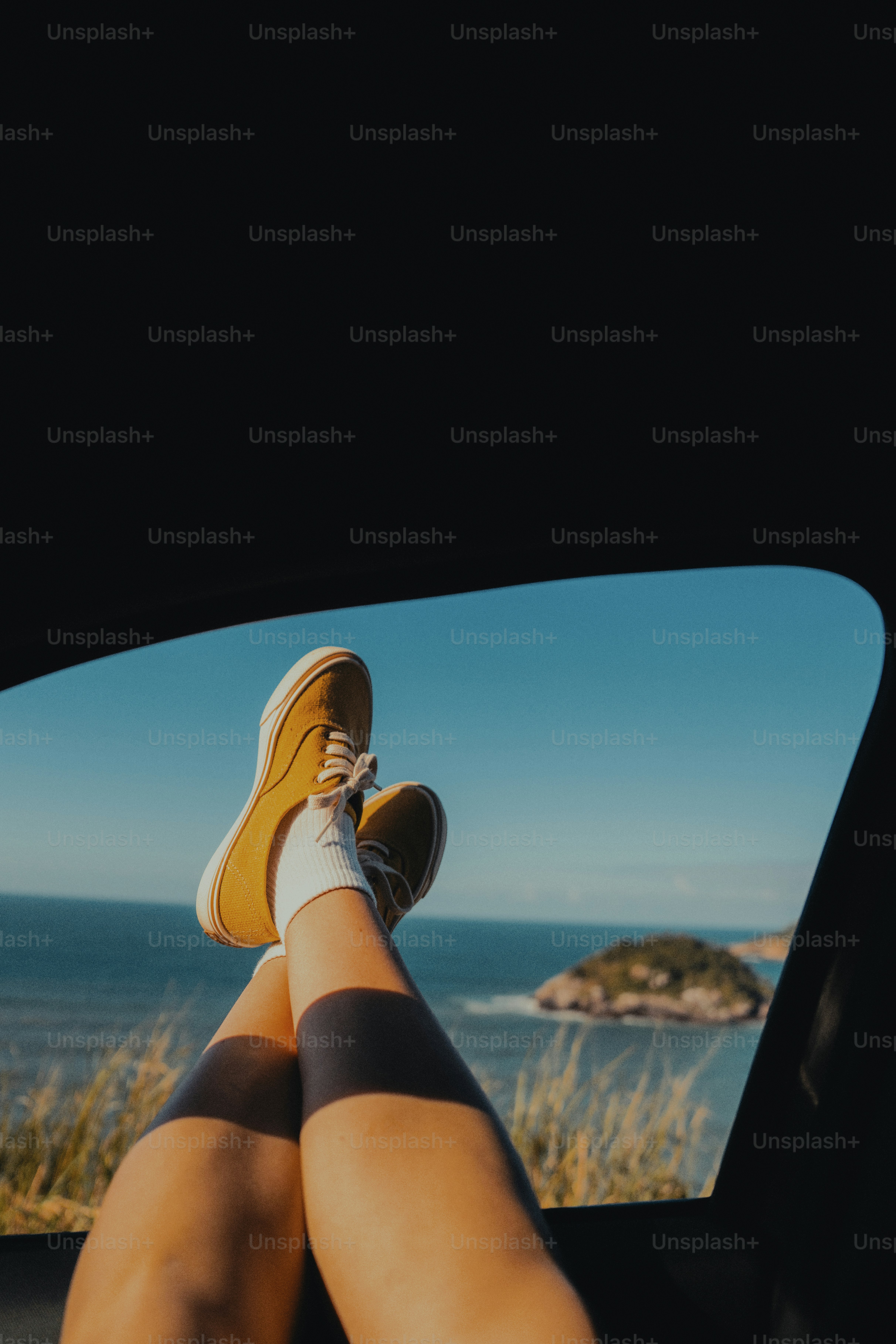 Yellow shoes out car window overlooking ocean