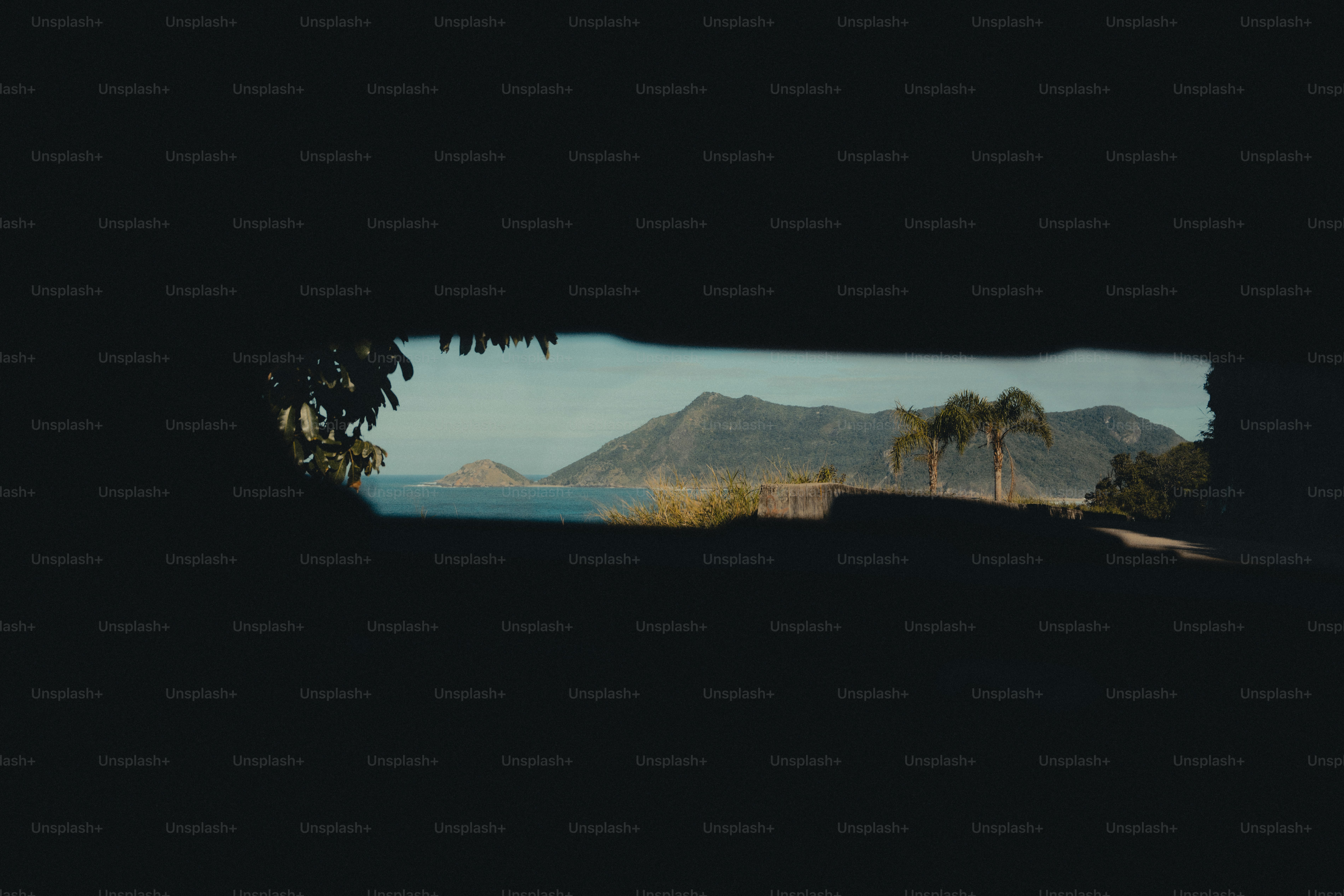 Paisagem tropical de montanhas e oceanos através de aberturas escuras