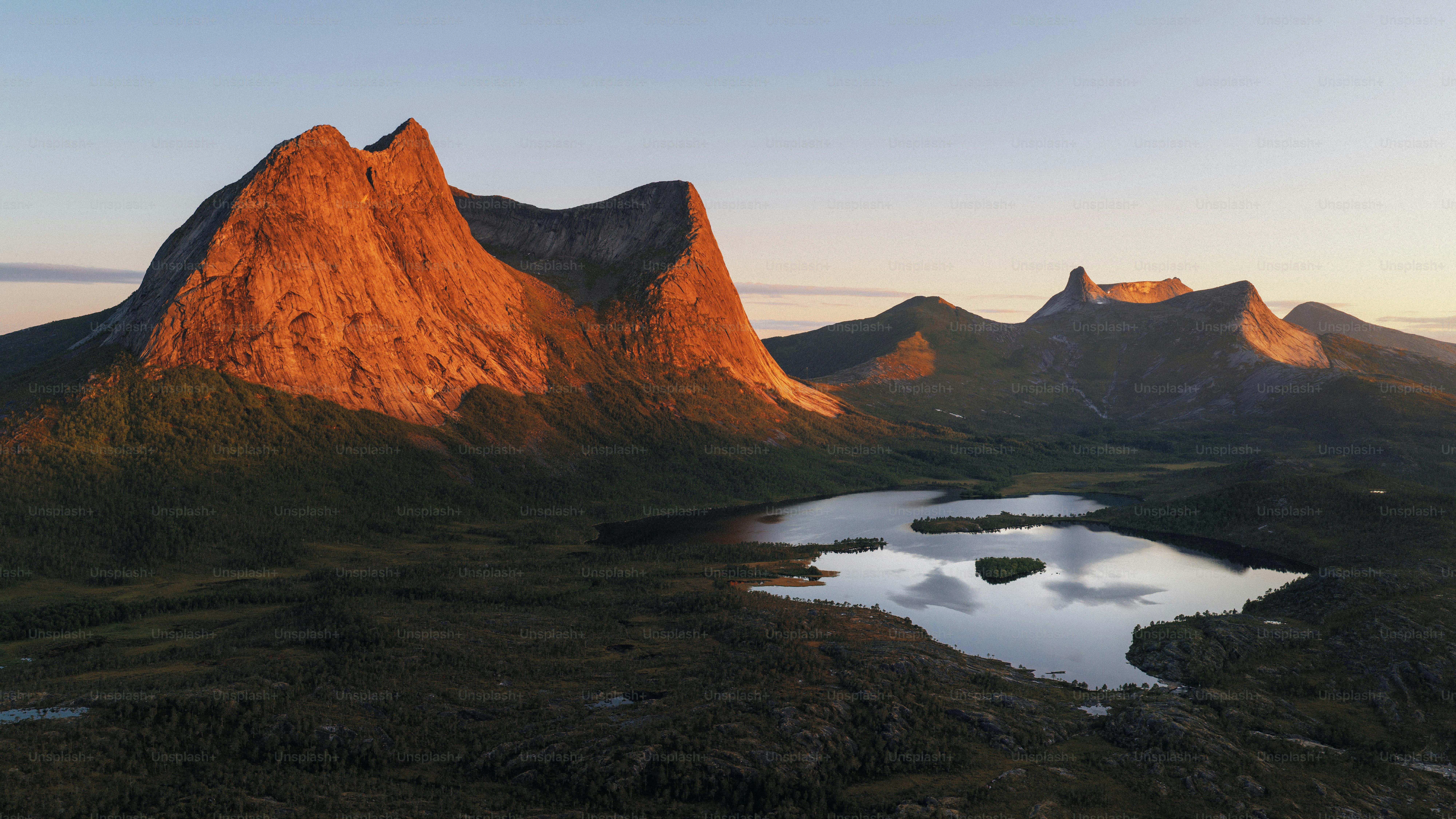 Sunlit mountains and still lake at golden hour