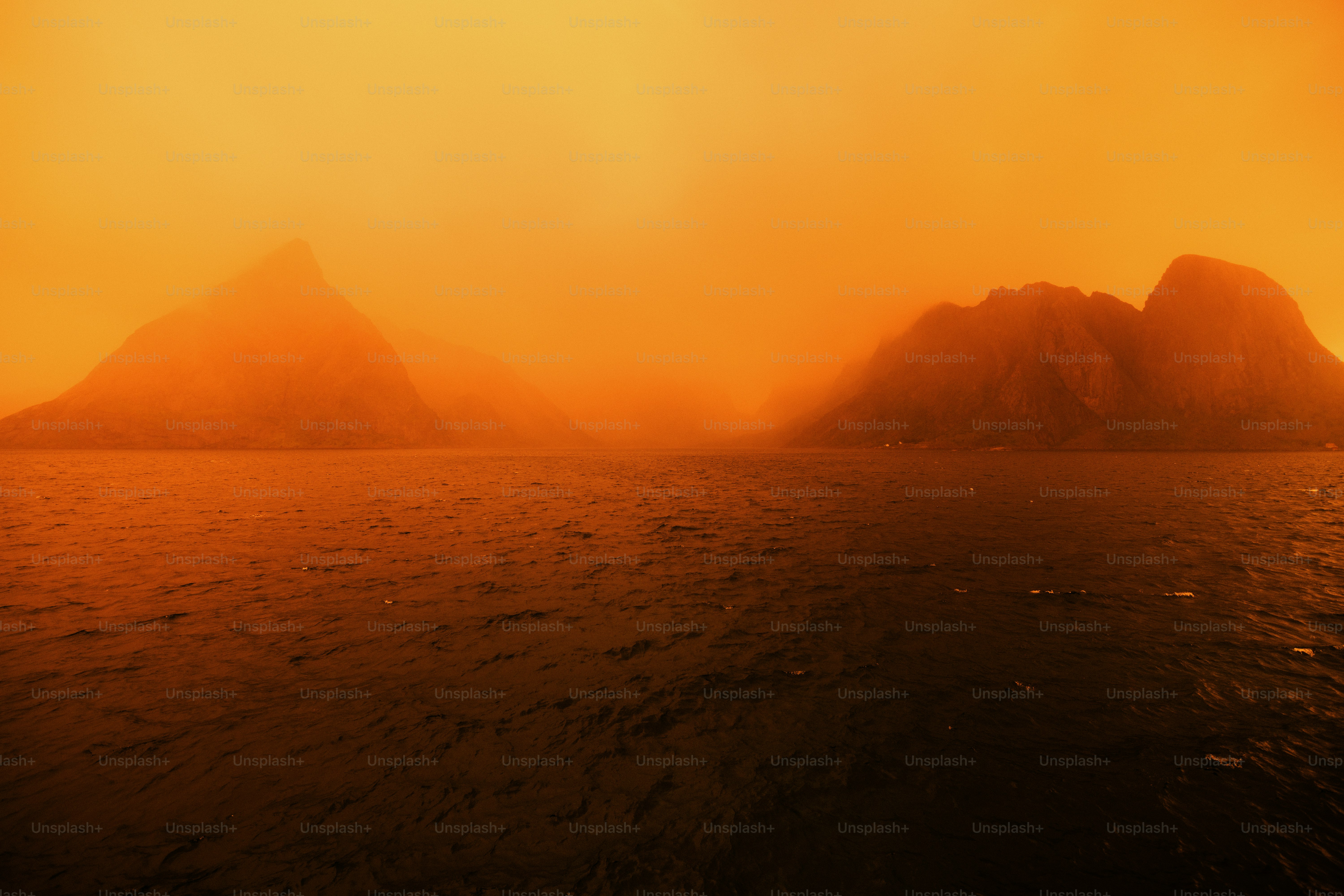 Hazy orange sky above islands and dark water
