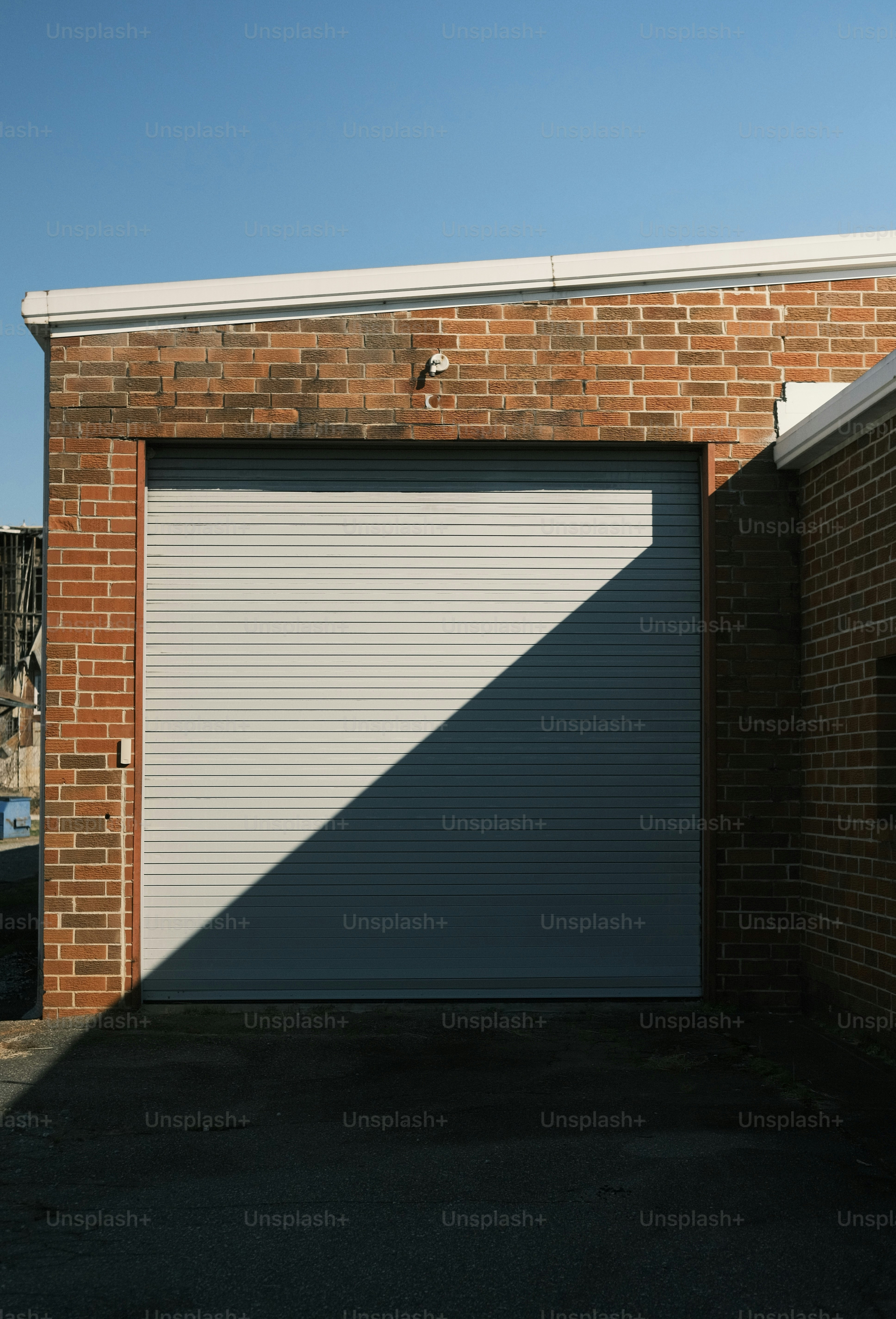 Ombra diagonale sulla porta grigia del garage di un edificio in mattoni