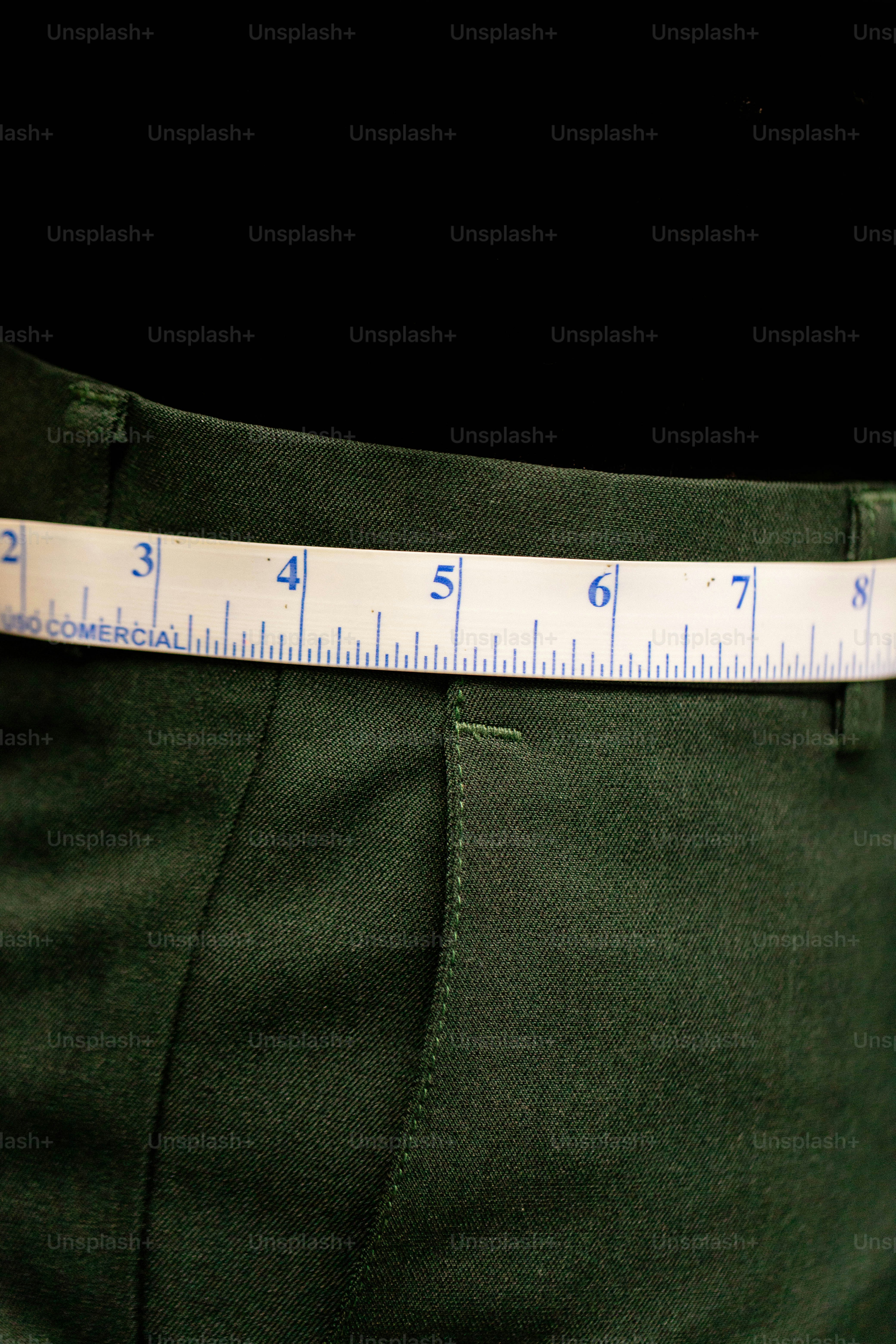 White measuring tape around waist of green pants