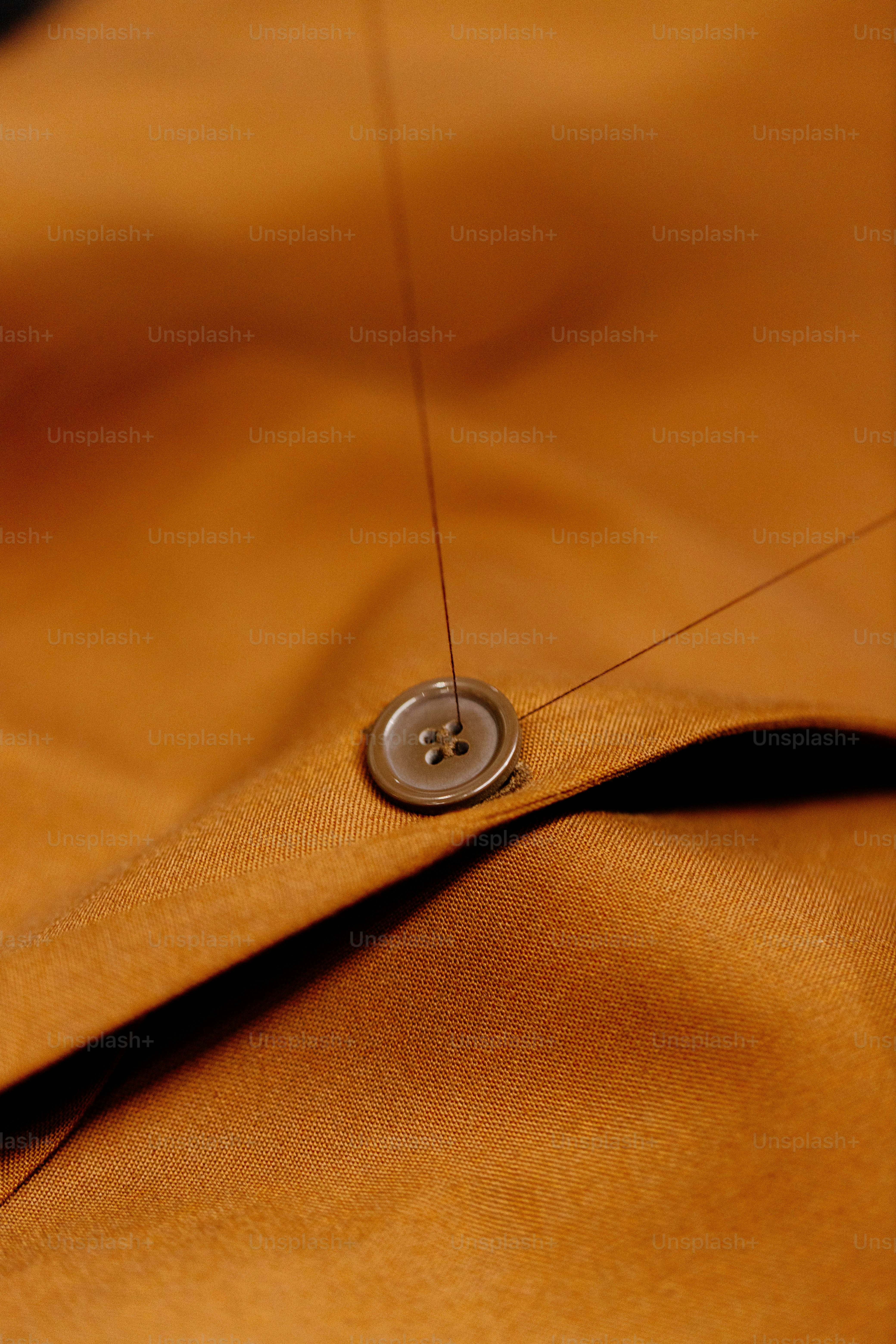 Sewing a button onto brown fabric