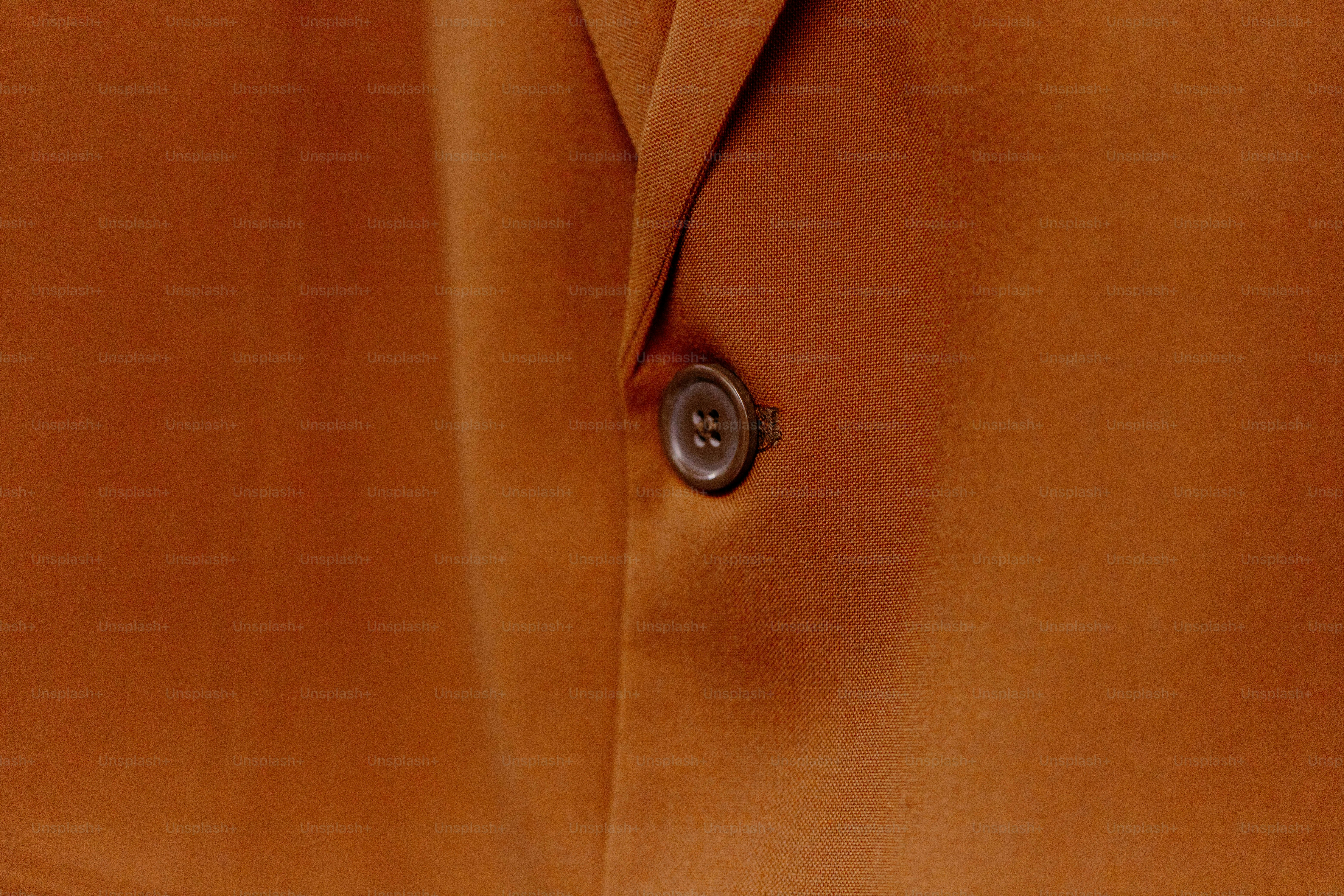 Single dark button on orange-brown fabric