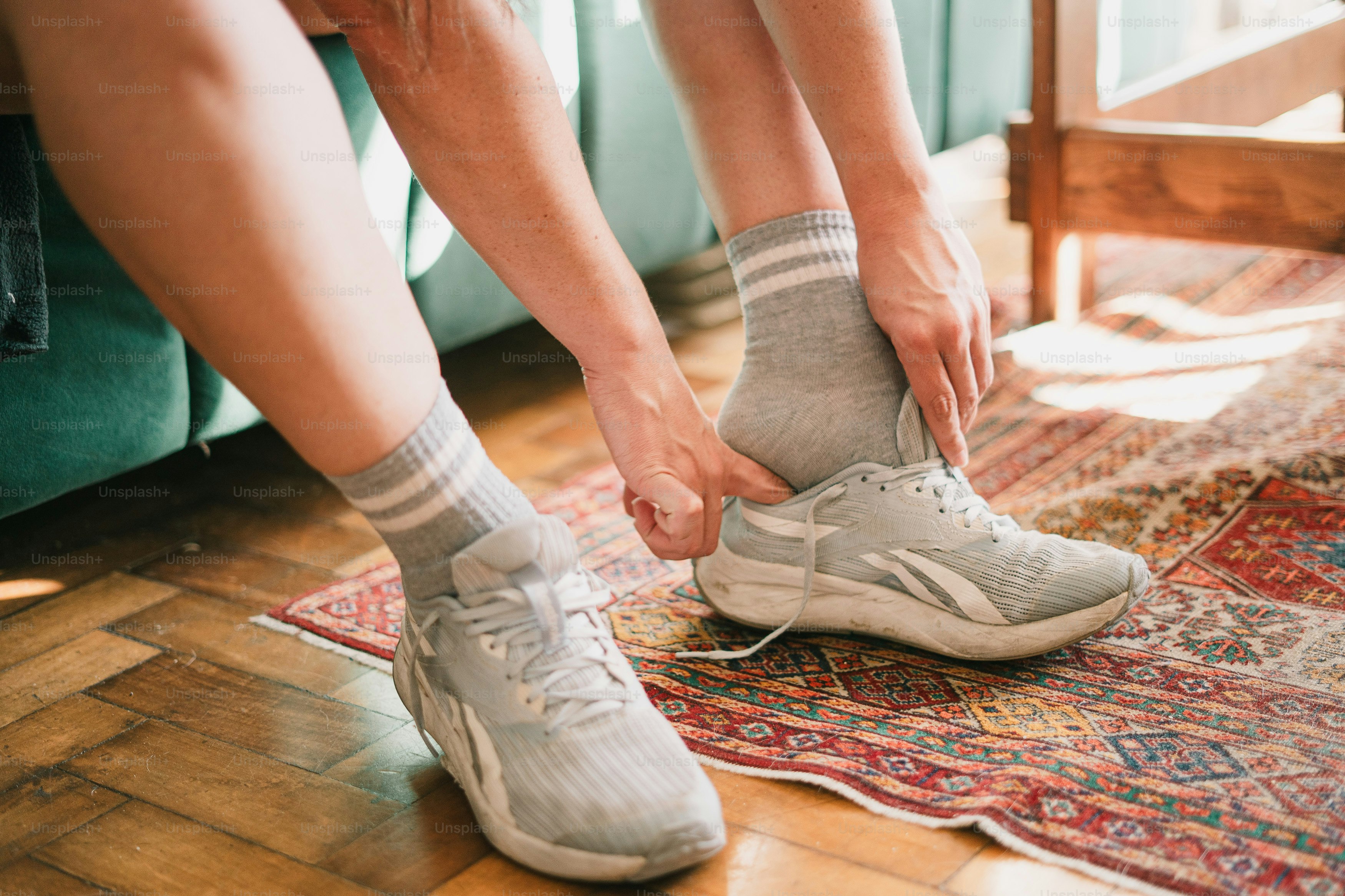 Personne qui enfile des baskets grises et des chaussettes rayées