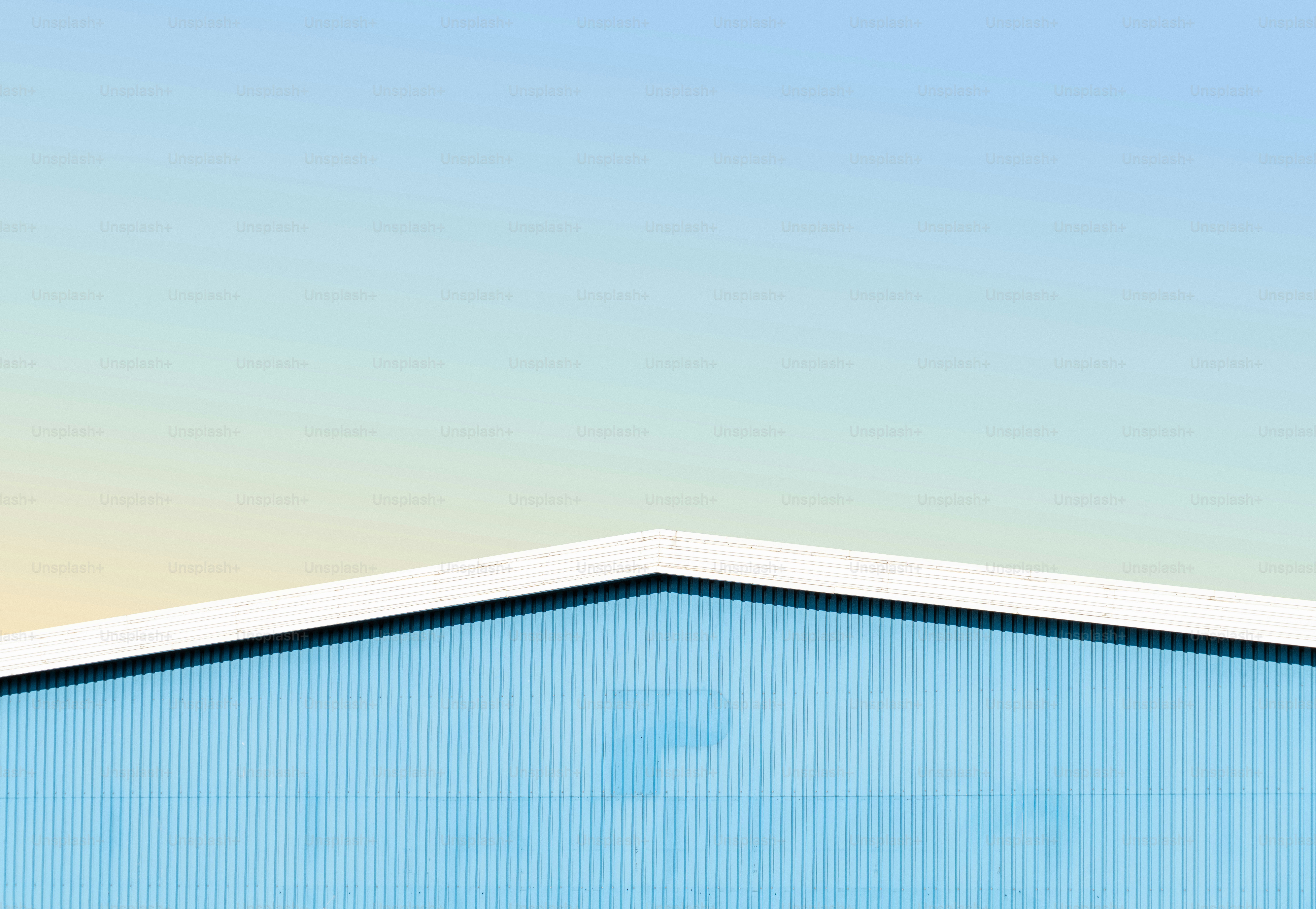 Blue building, white peaked roof, gradient sky