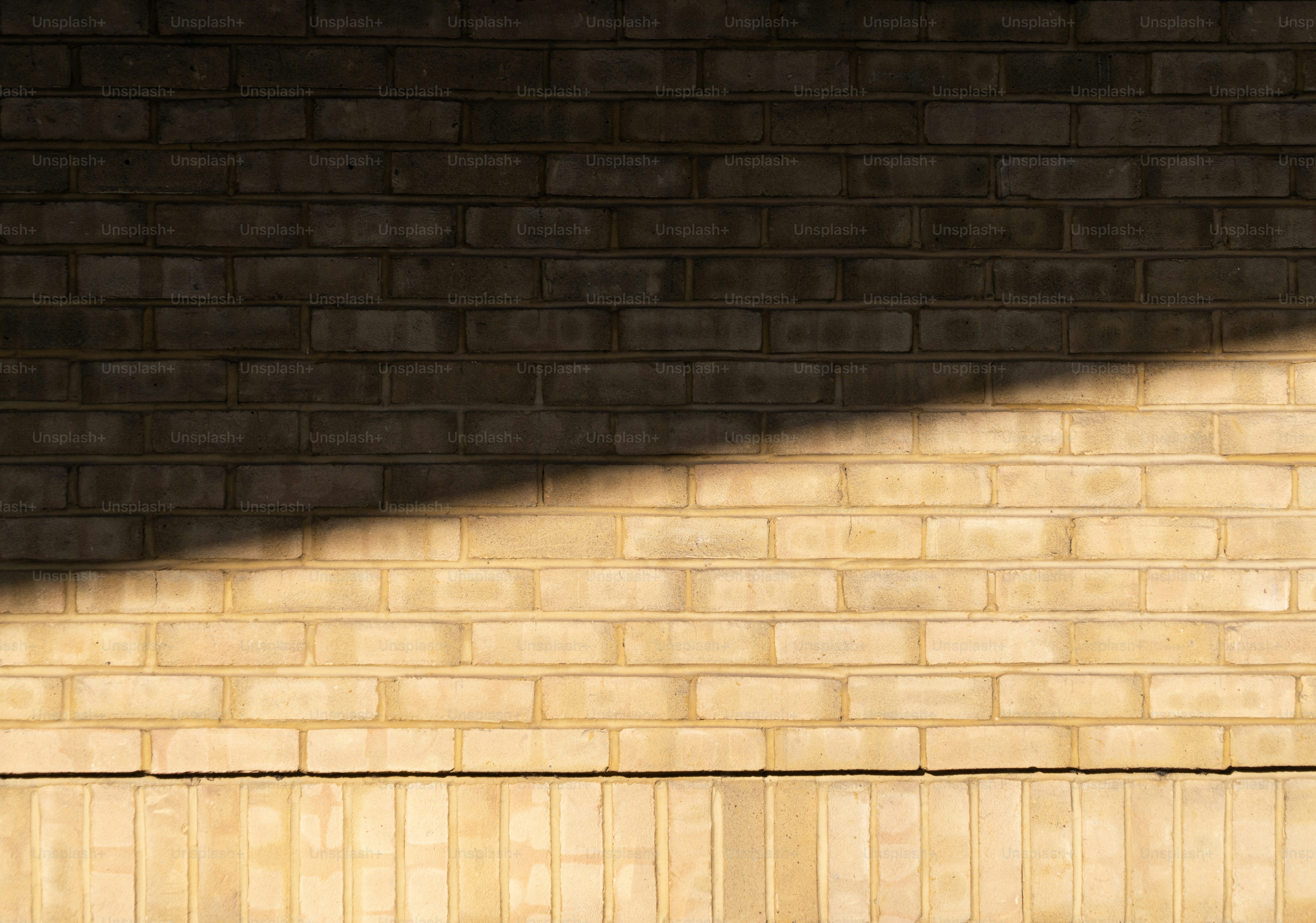 Sunlight casting diagonal shadow on brick wall