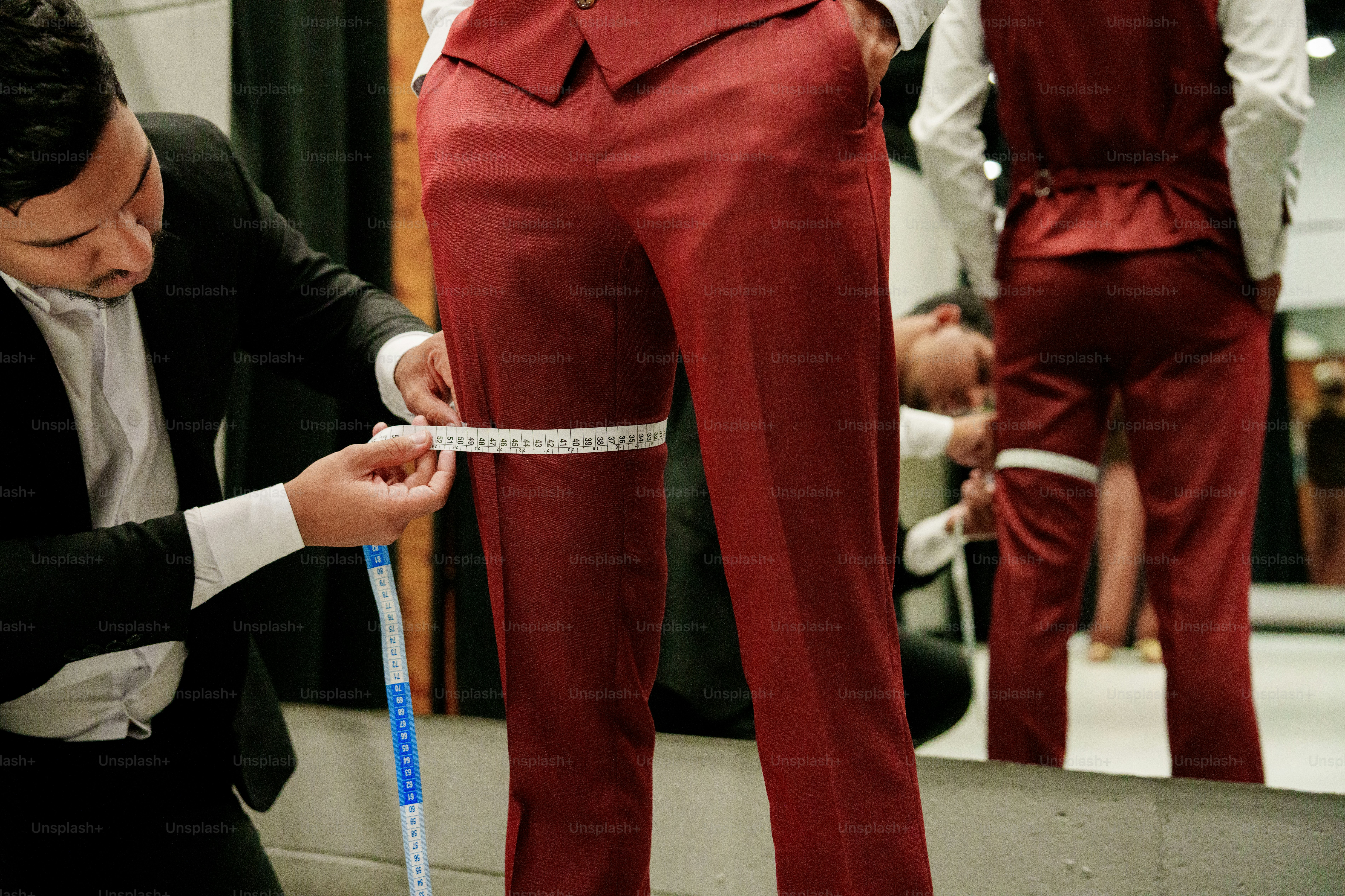 Tailor measuring a man's thigh for red pants