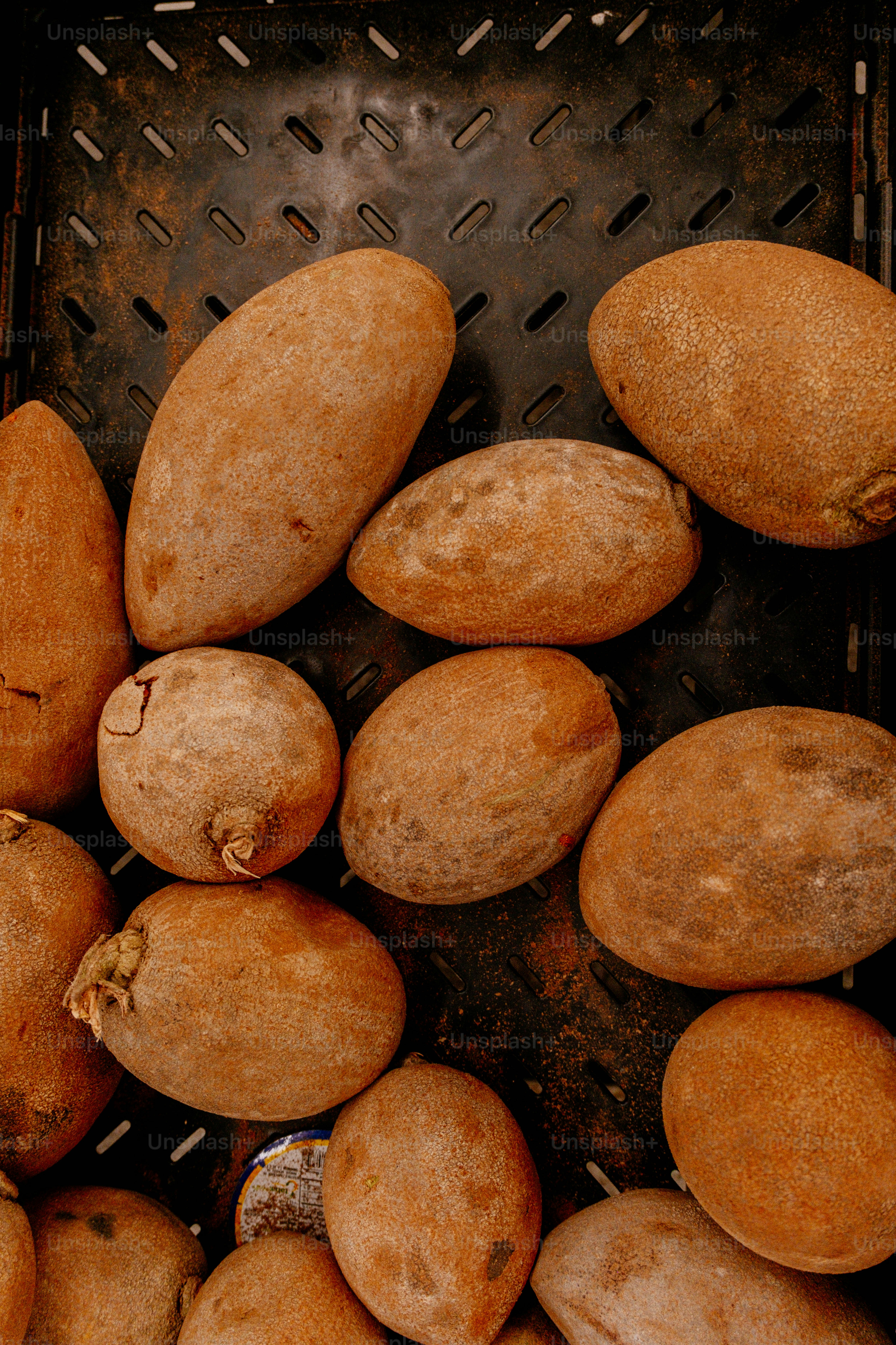 Oval brown fruits in a dark textured crate