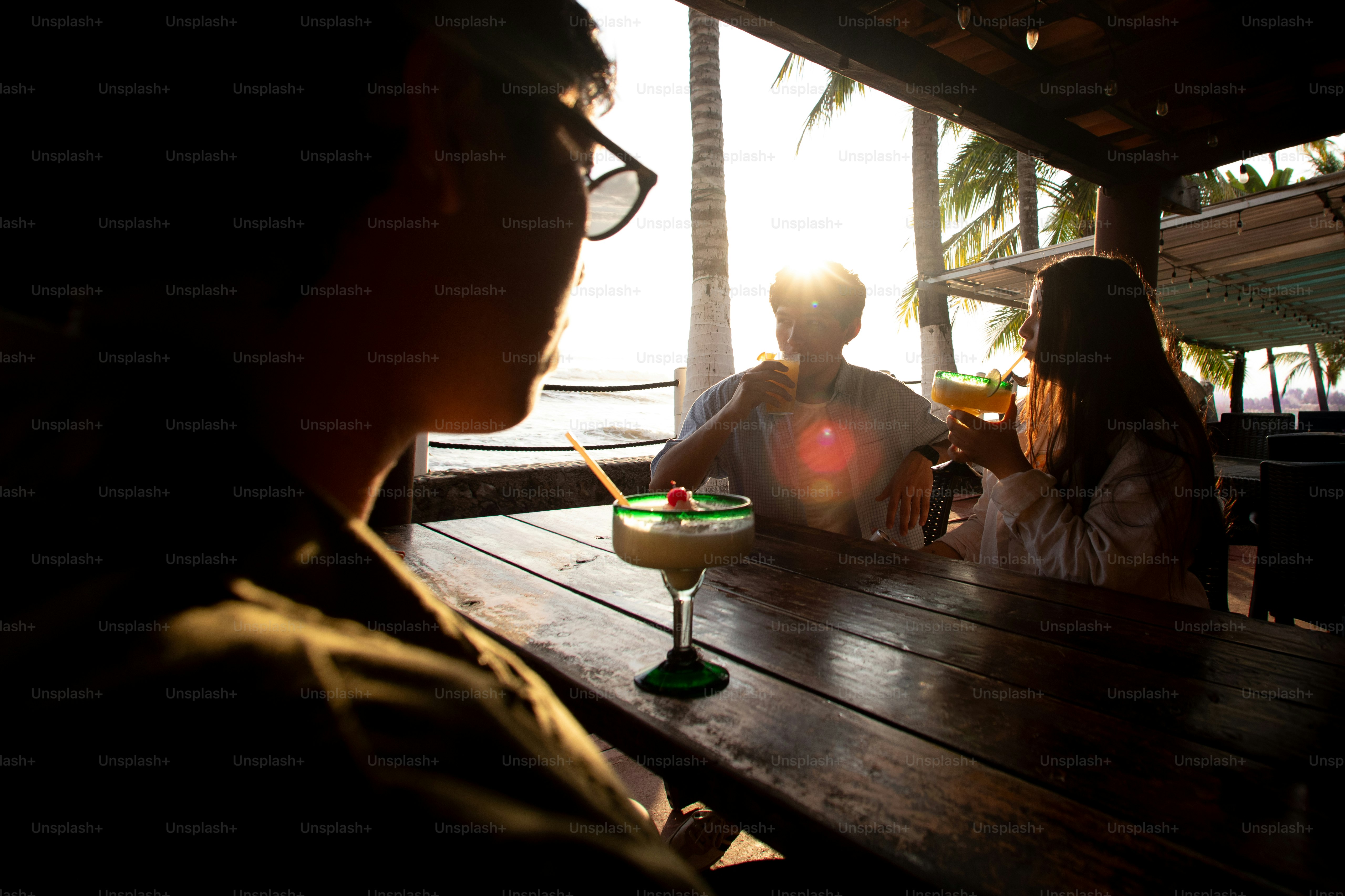 Des amis en silhouette profitant de cocktails dans un bar de plage