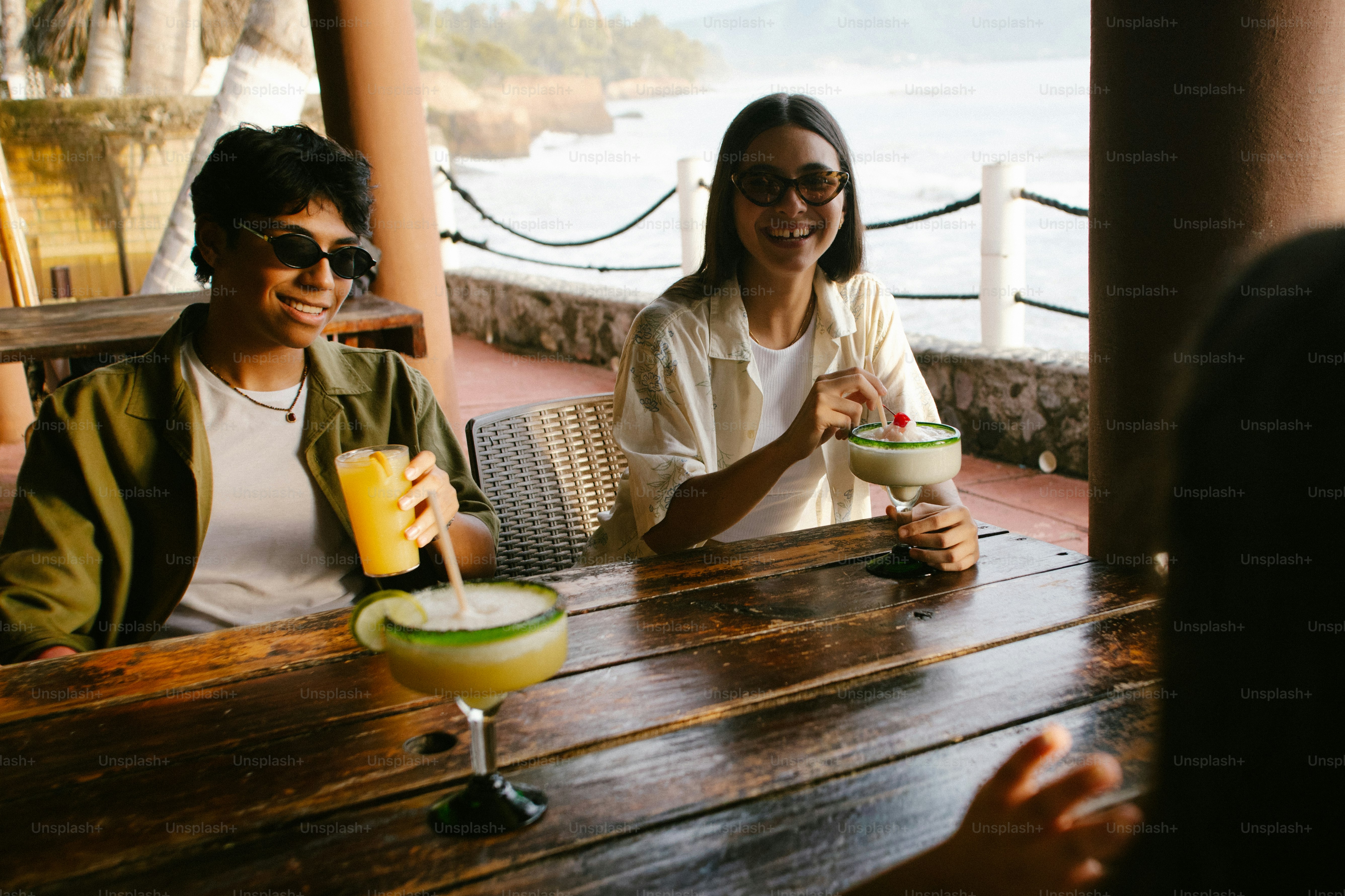 Des amis heureux en train de boire des cocktails dans un café au bord de la mer