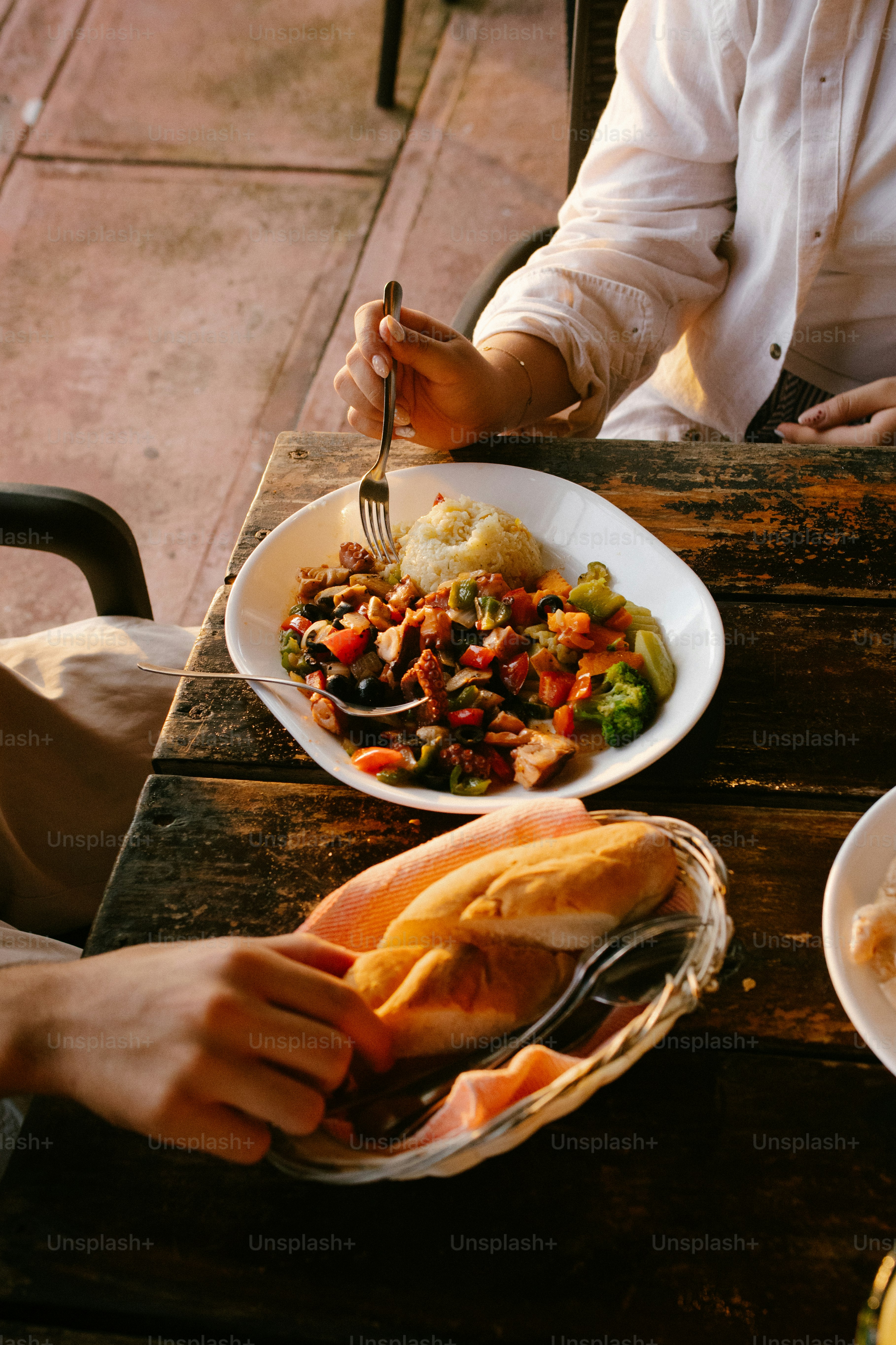 Des gens mangeant le repas et le pain sur une table rustique en bois