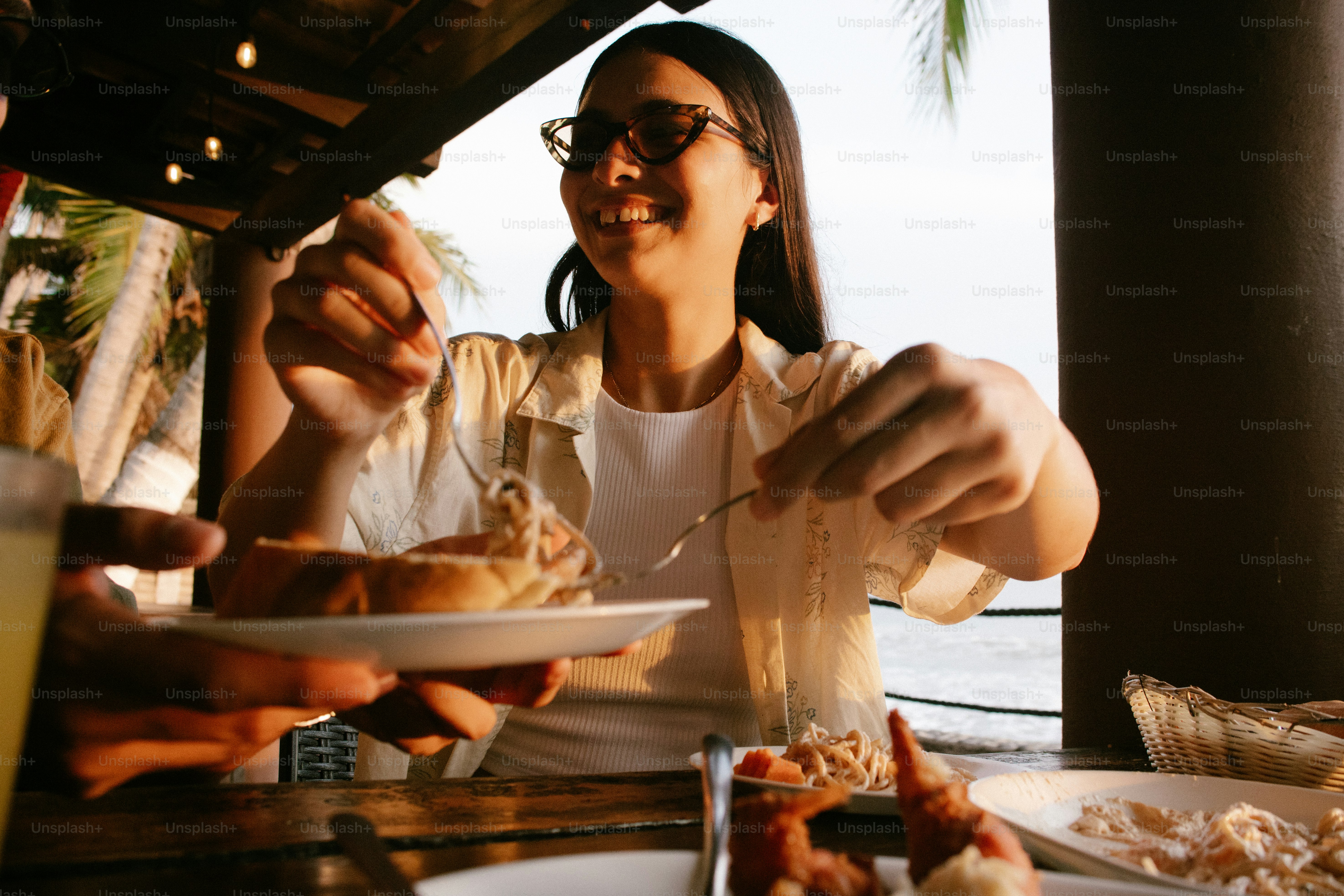 Femme heureuse mangeant dans un restaurant en plein air au bord de l’eau
