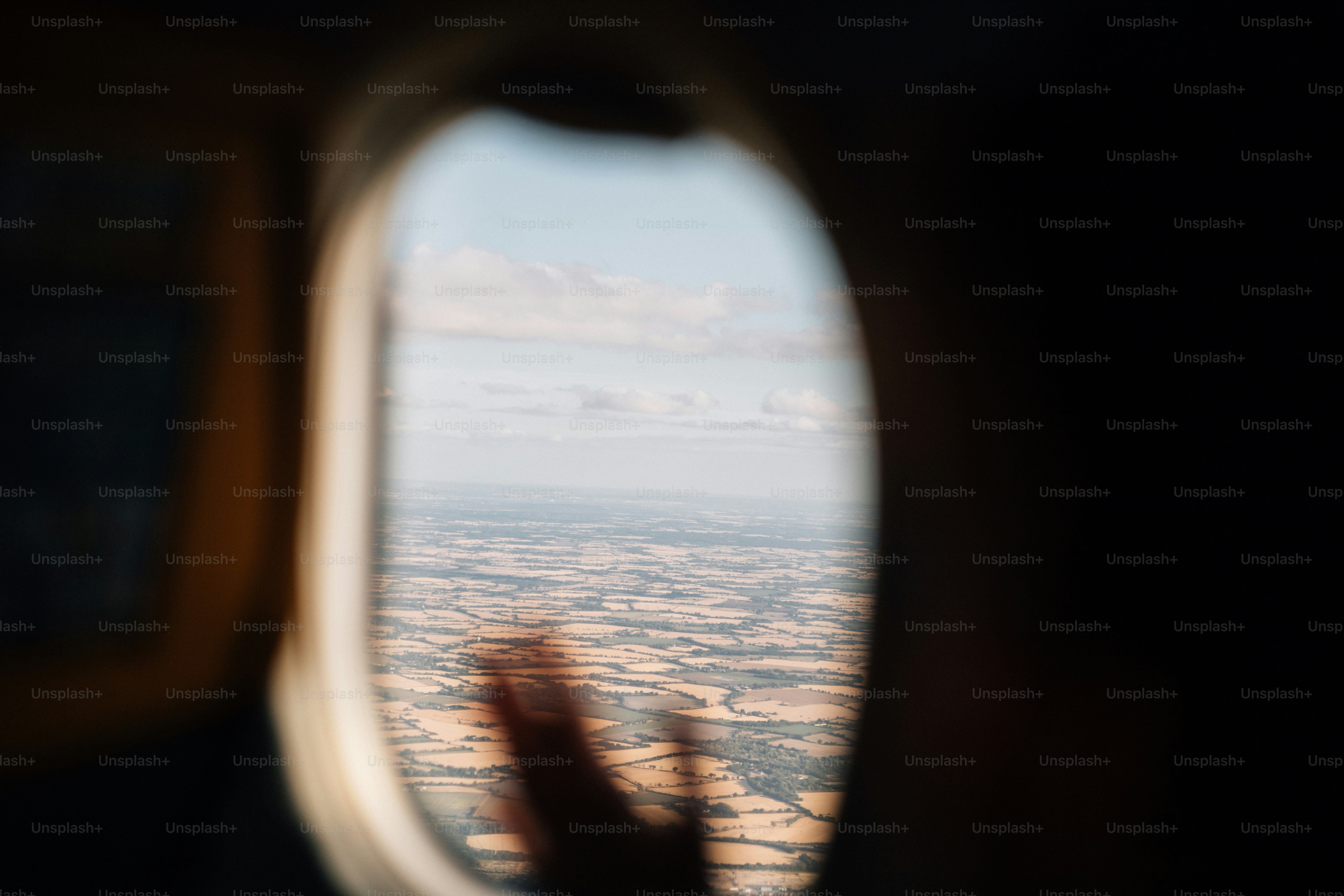 Unscharfe Hand und Landschaft durch Flugzeugfenster