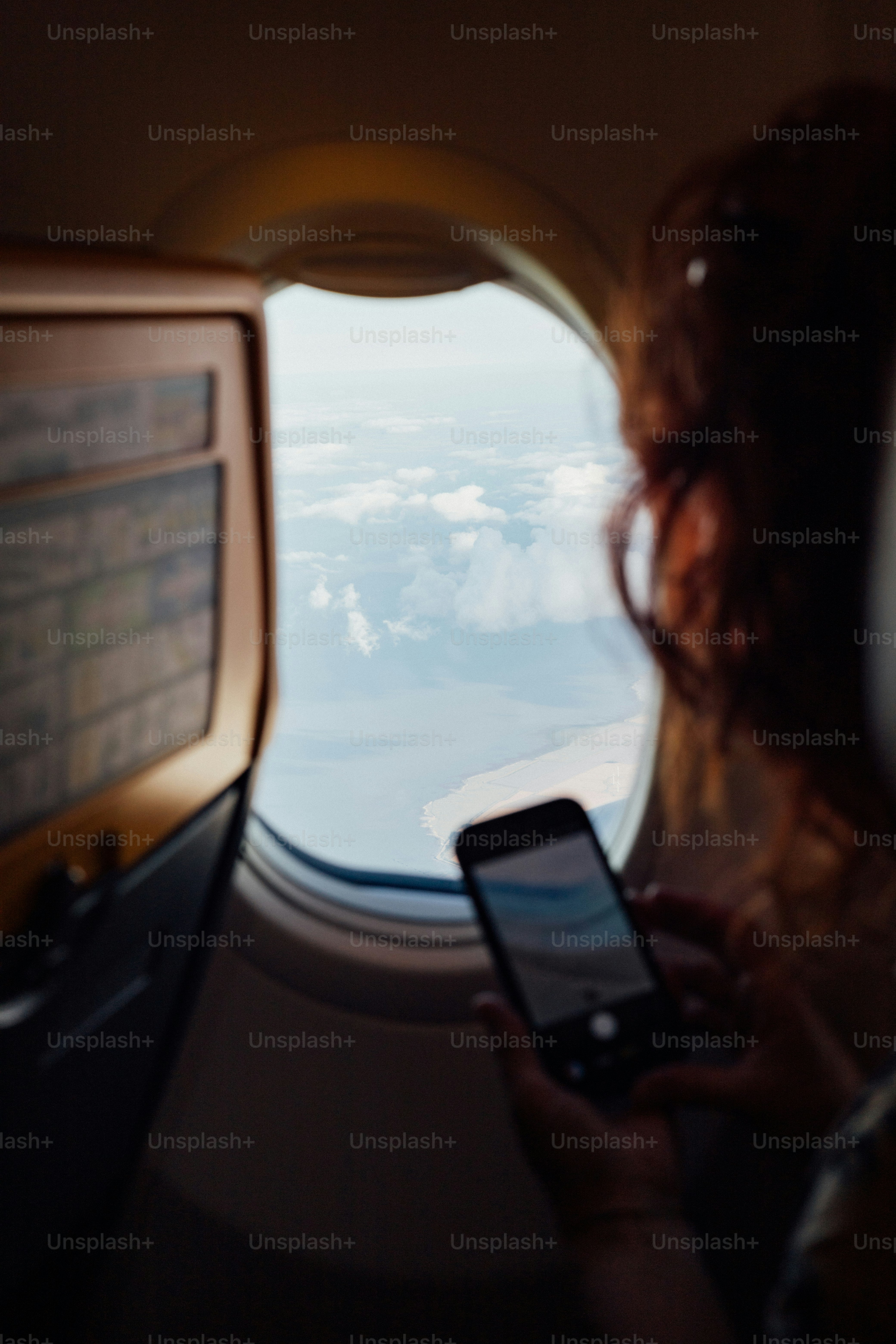 Passenger photographing clouds and ocean from airplane window