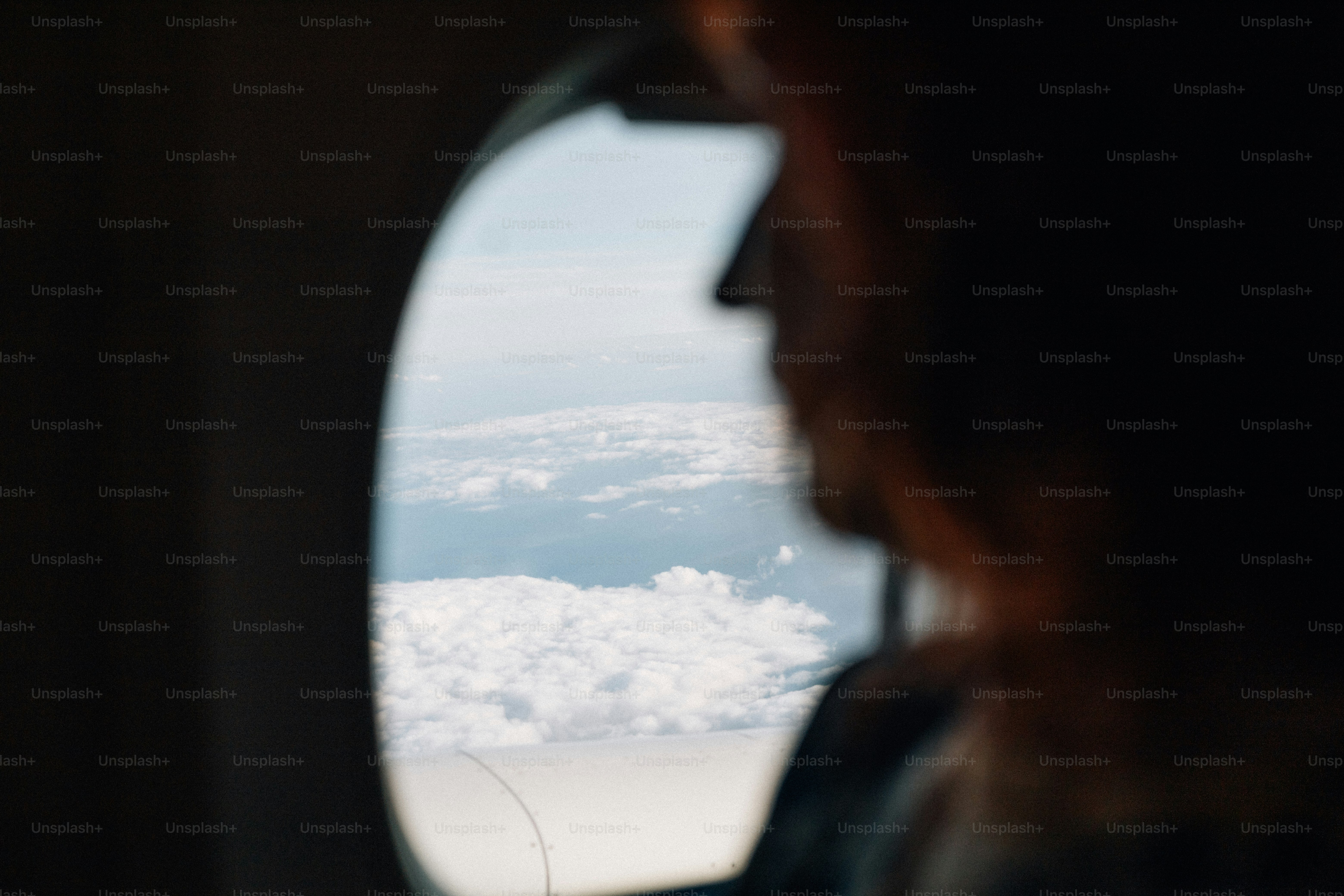 Silhouette, die aus dem Flugzeugfenster auf die Wolken blickt