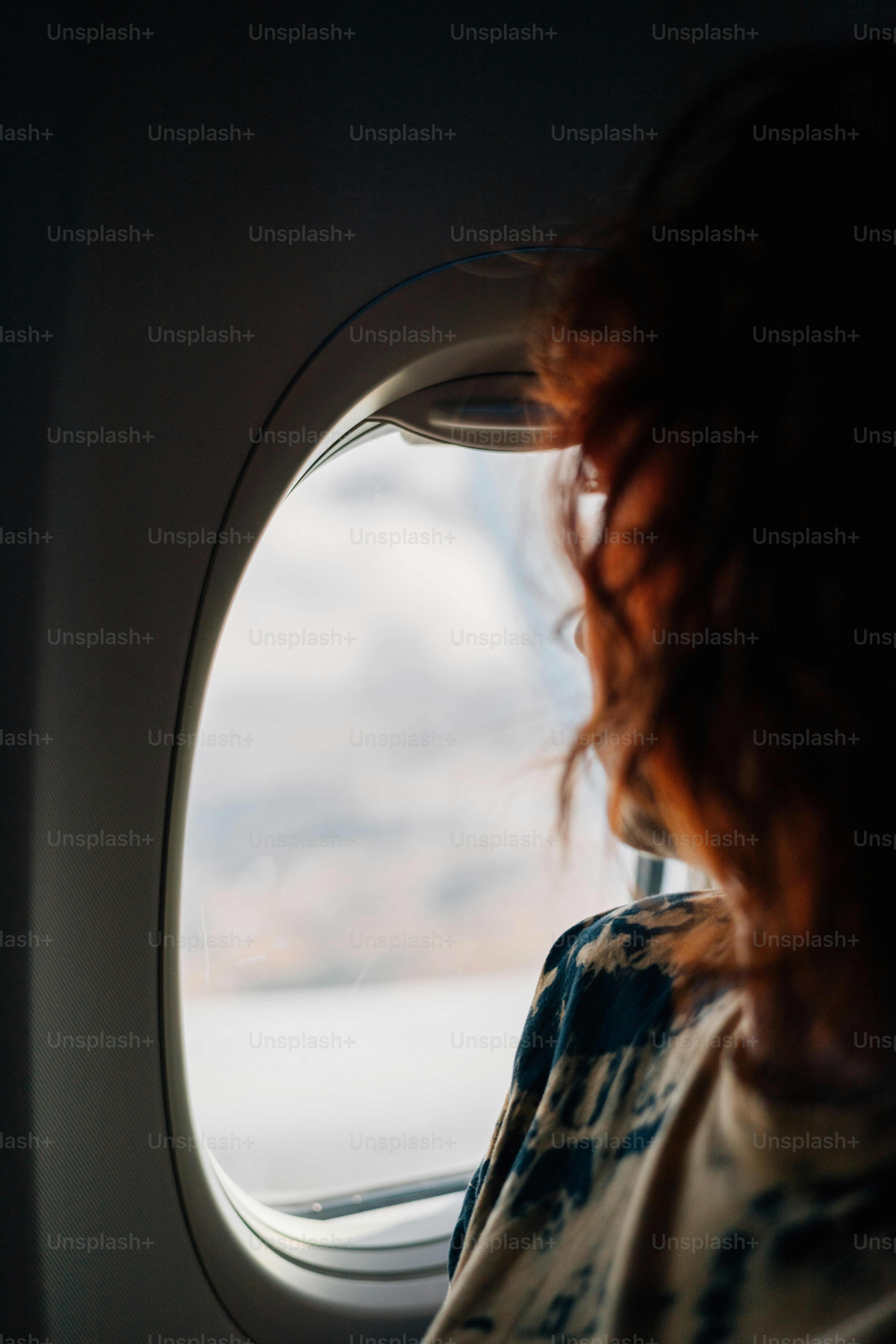 Reisender mit roten Haaren blickt aus dem Flugzeugfenster