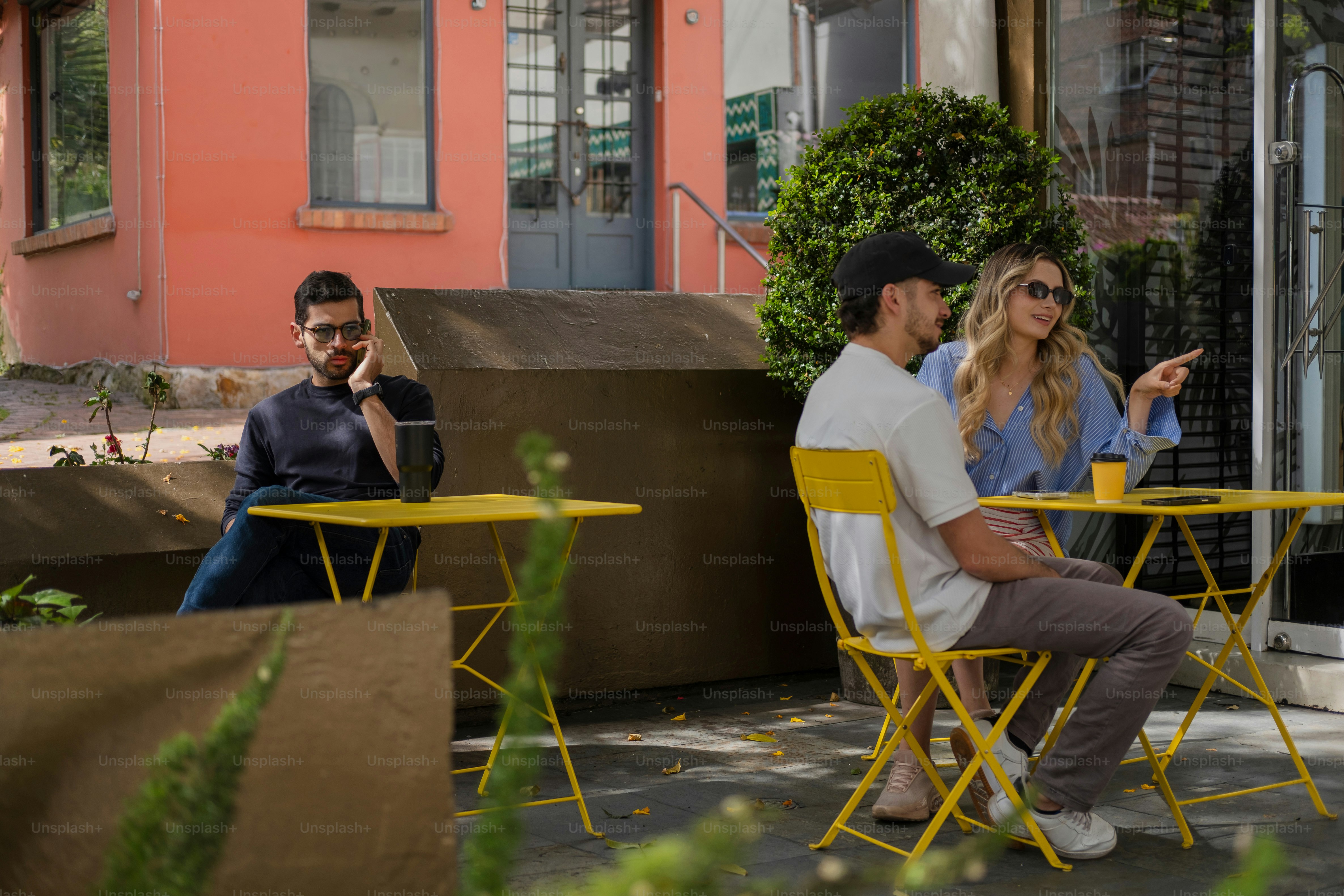 Des gens assis aux tables jaunes du café en plein air