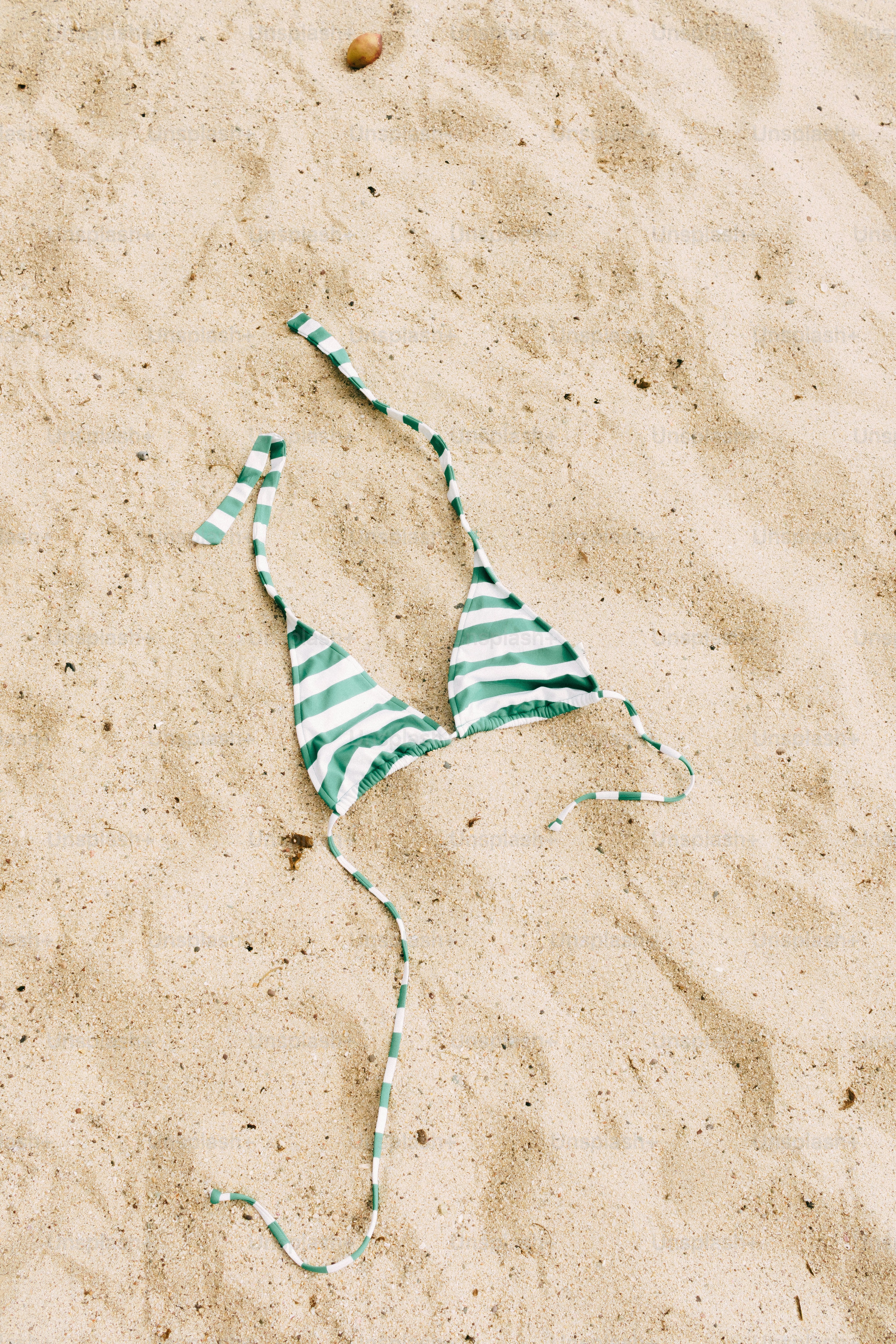 Blusa de biquíni listrada verde e branca sobre areia