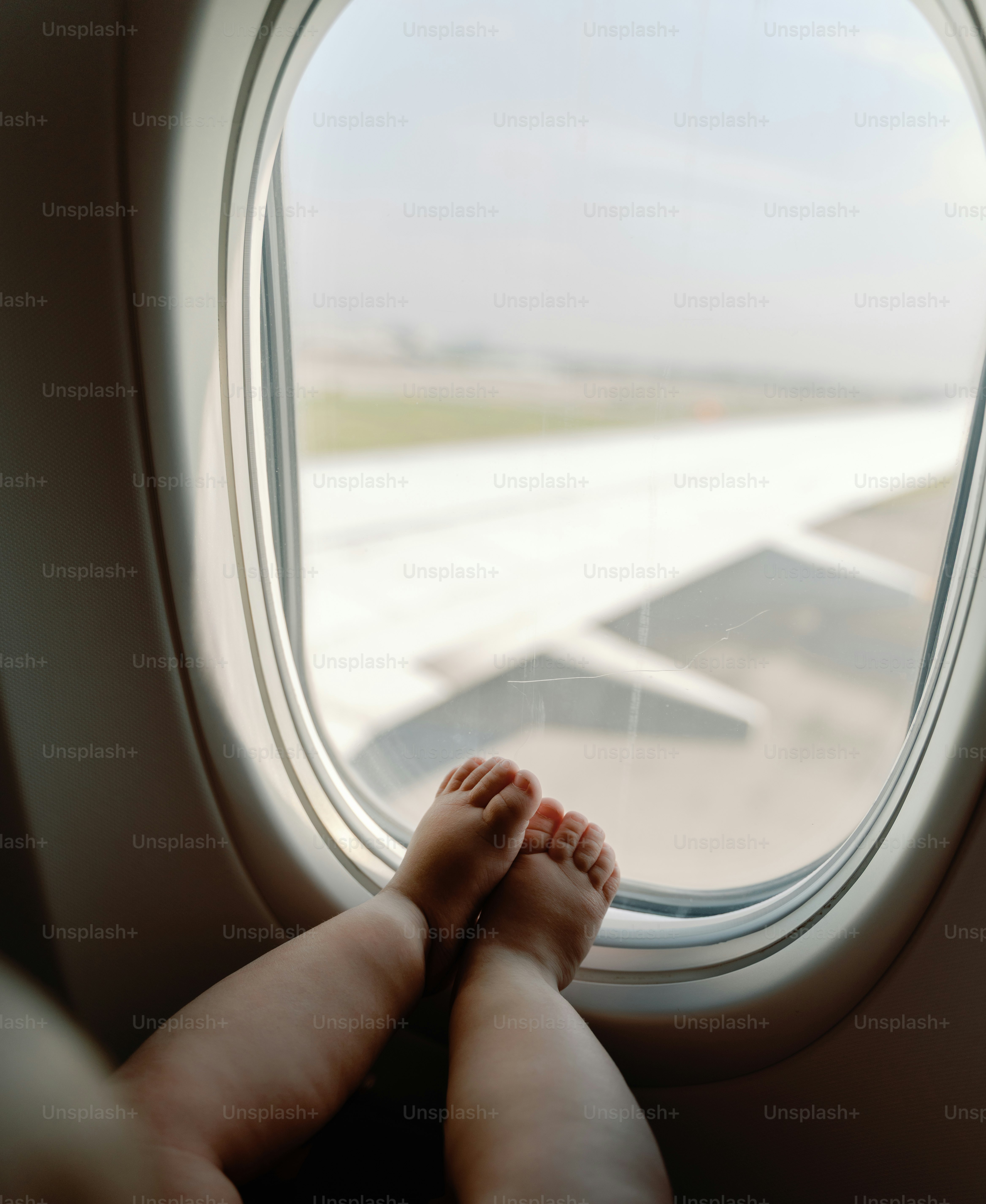 Piedi di bambino al finestrino, all'ala e alla pista dell'aereo