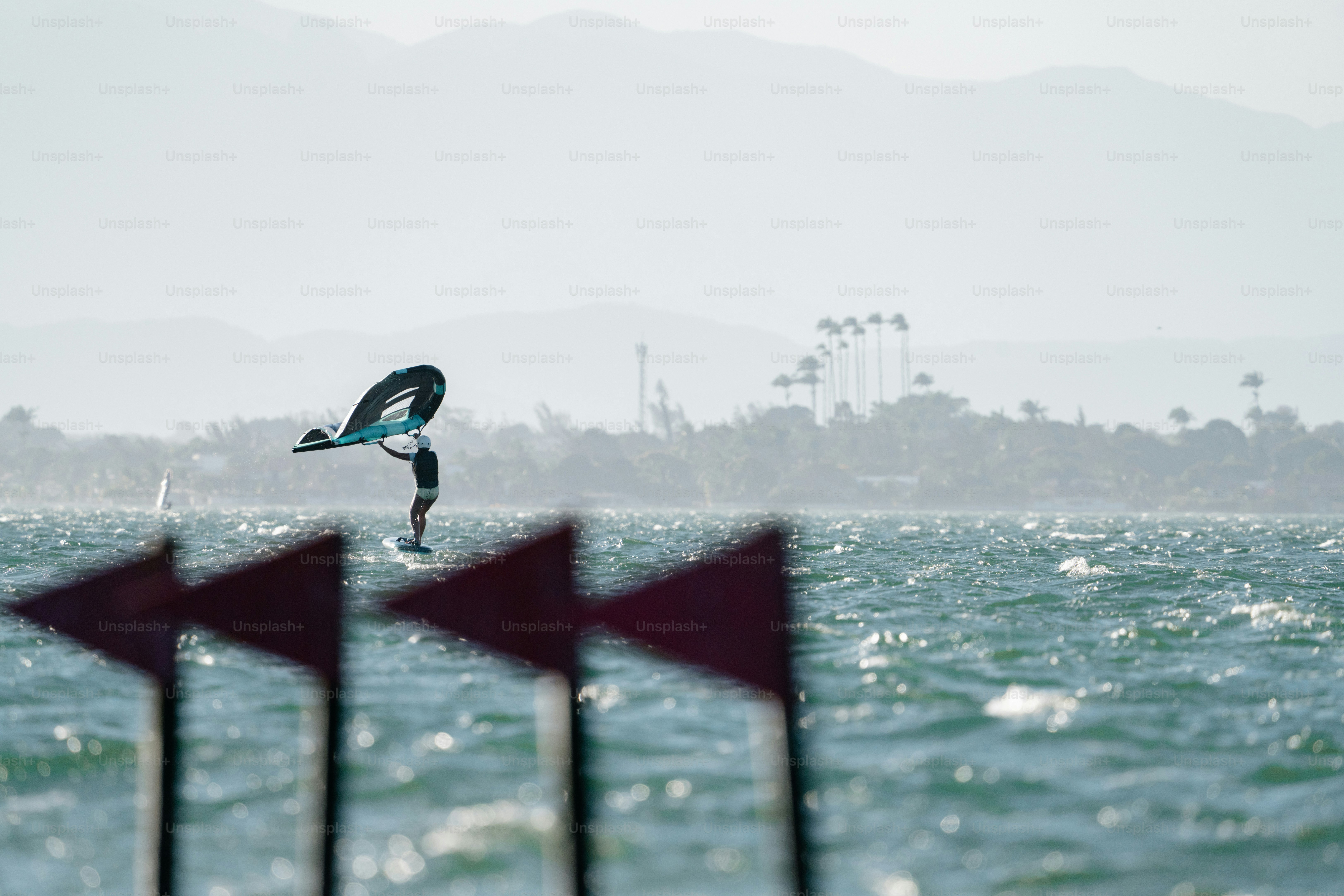 Person wing foiling on choppy water, red flags