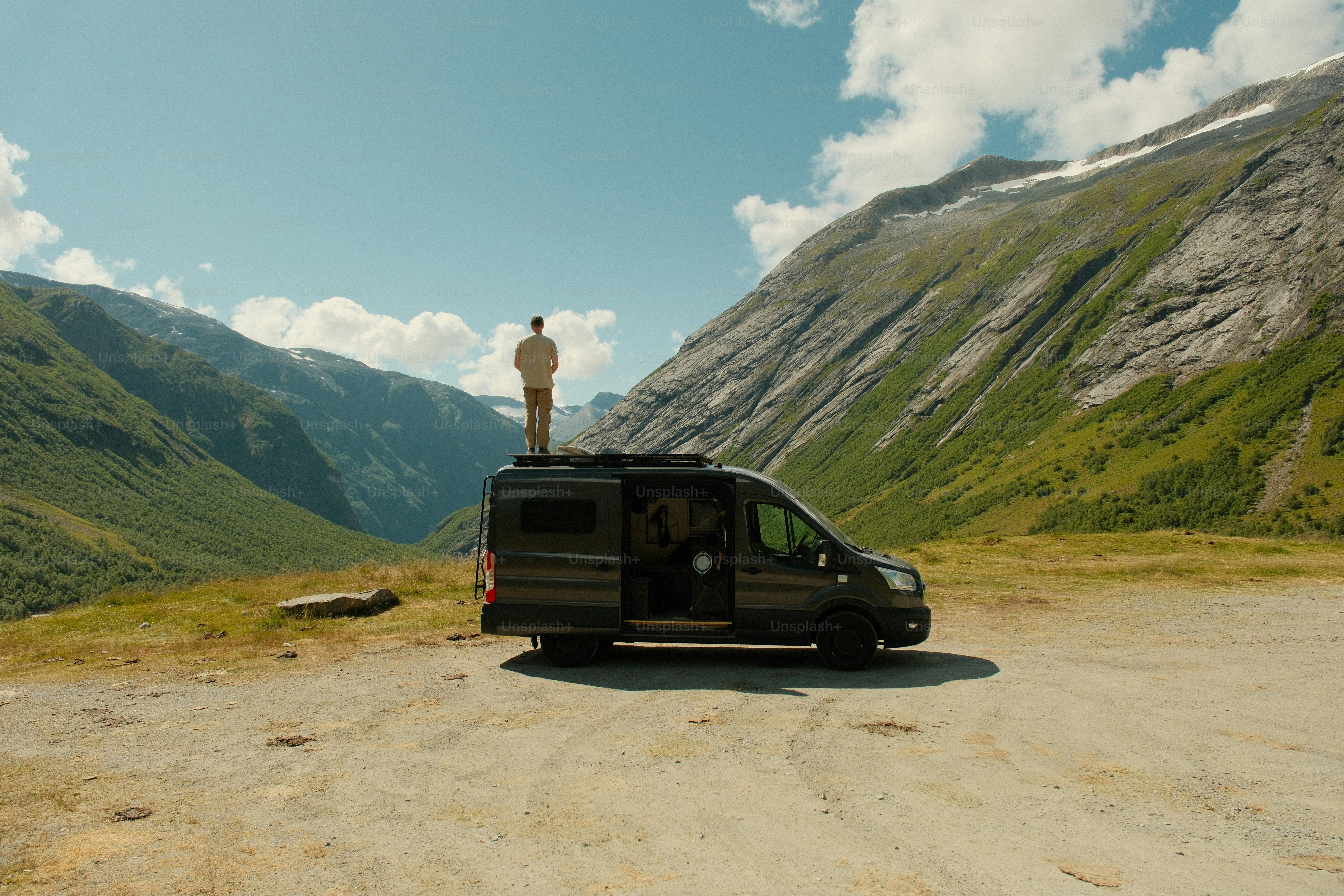 Person on camper van enjoying mountain landscape