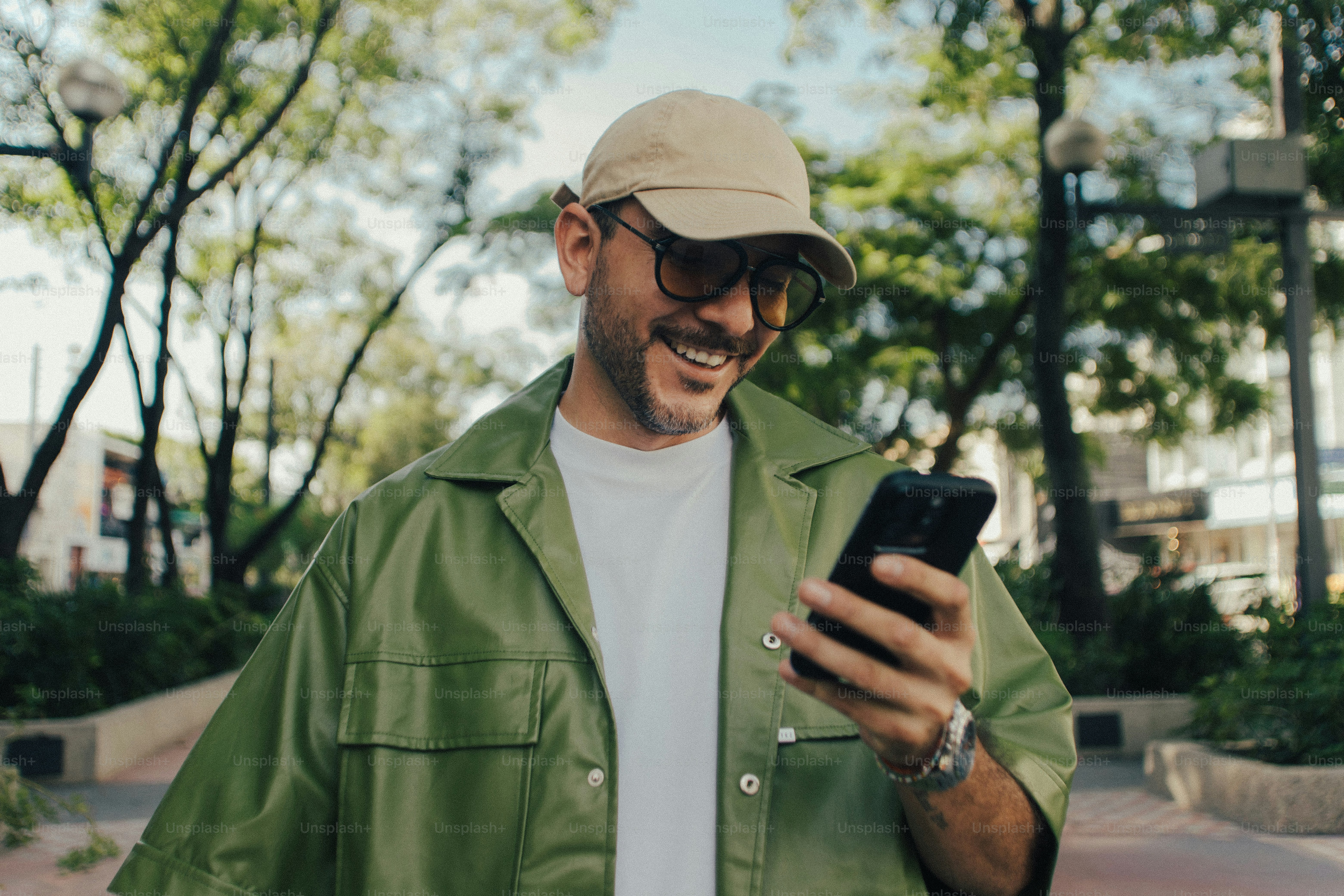 Man smiling at phone in cap and sunglasses