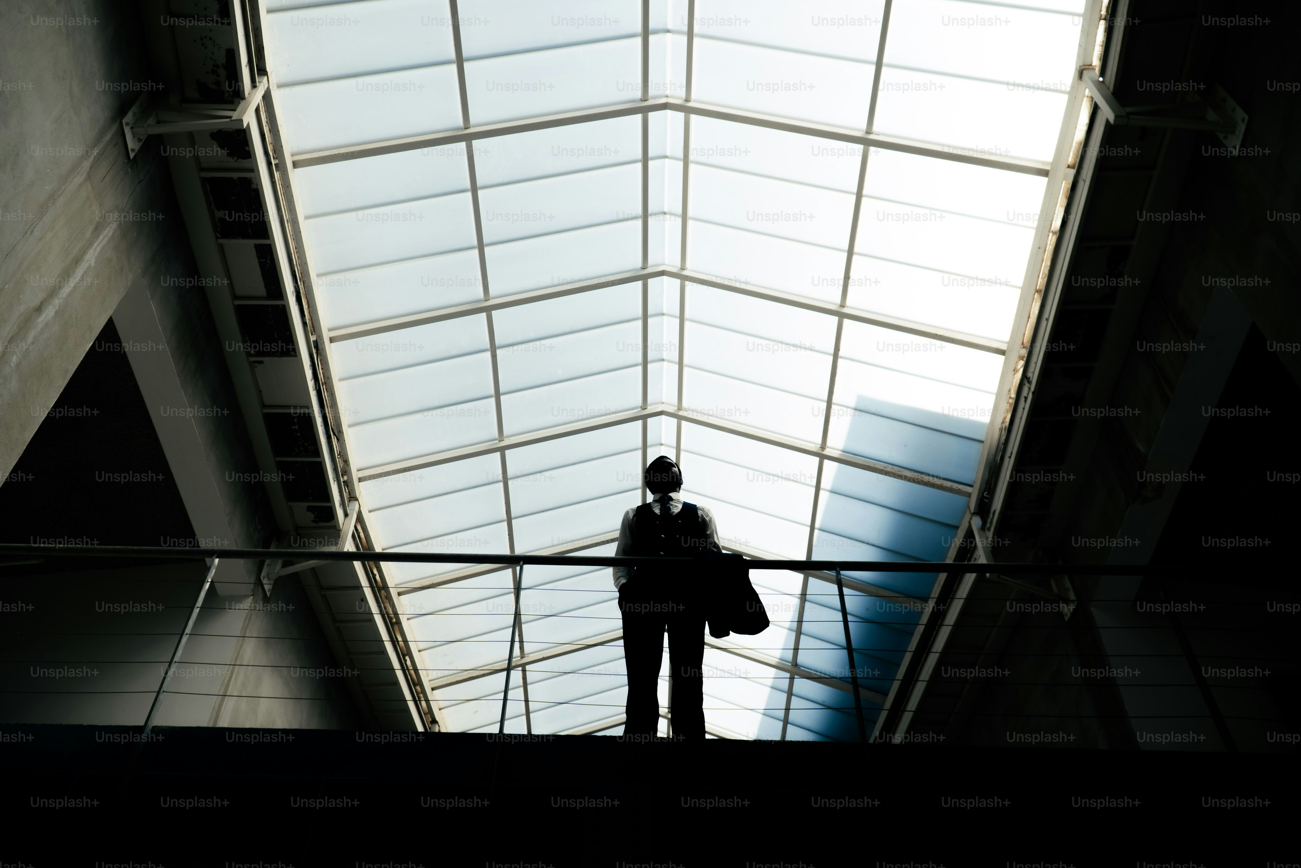 Silhouette di persona sotto un soffitto di vetro luminoso