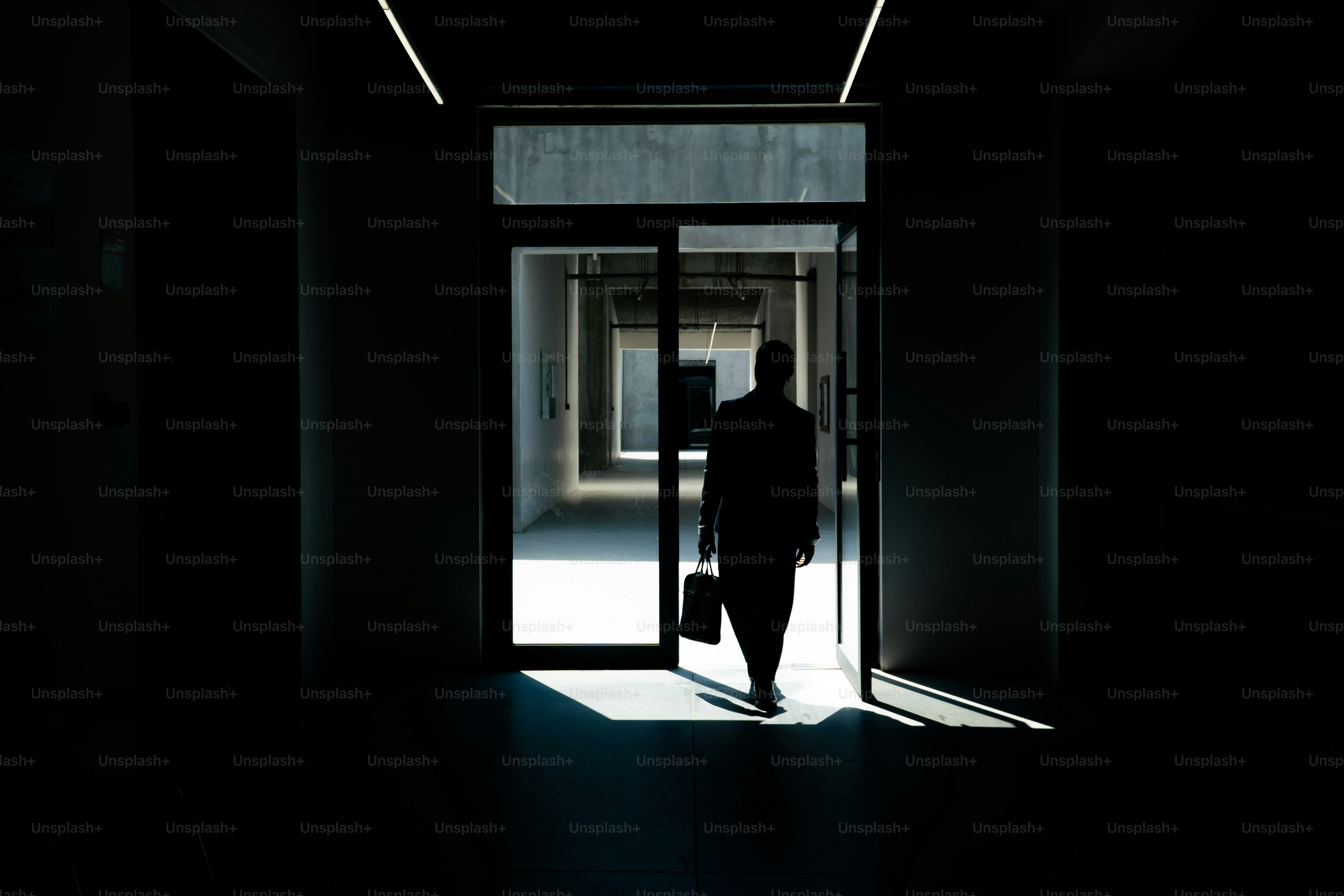 Silhouettenhafter Geschäftsmann geht durch die Tür ins Licht