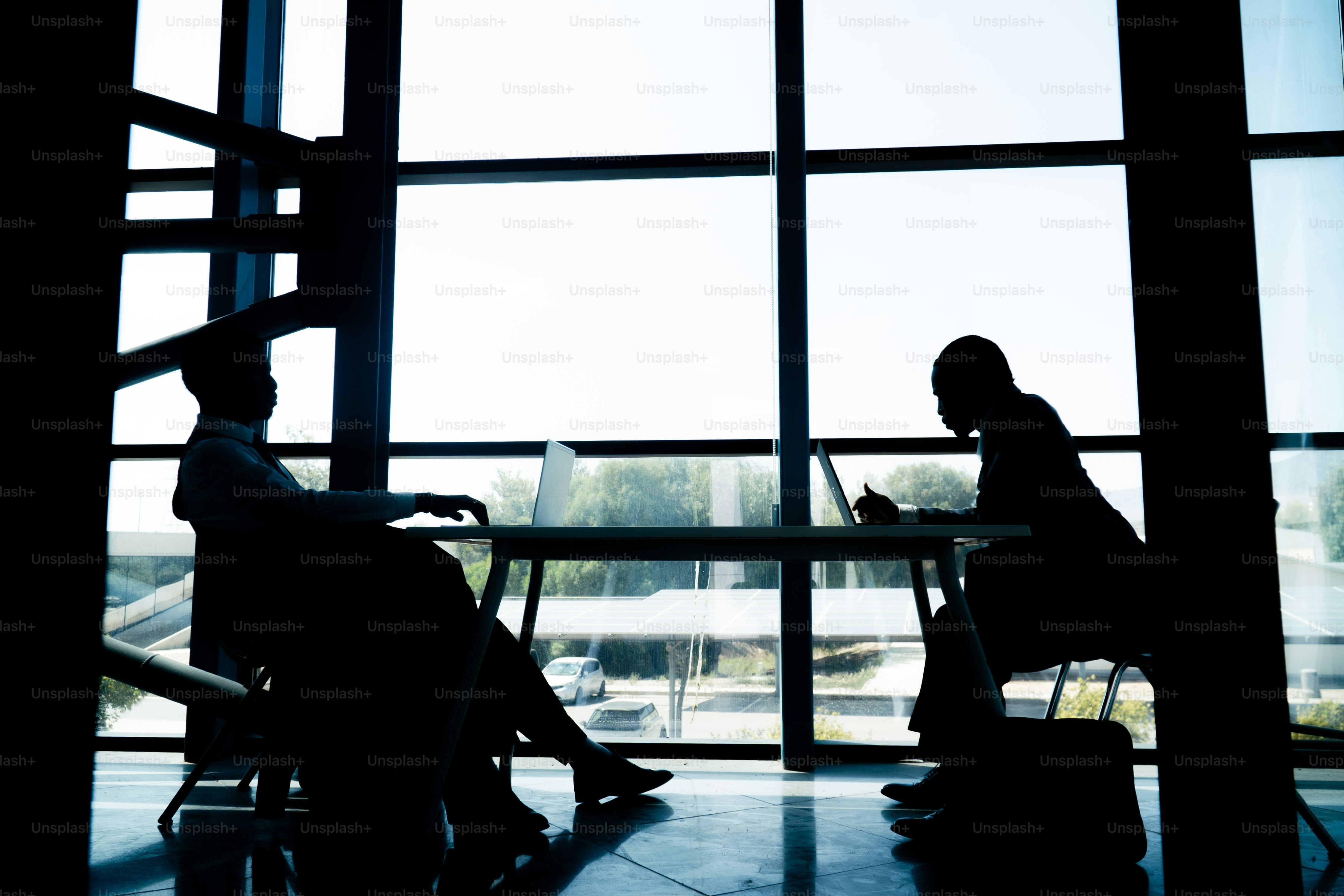 Silhouettenierte Geschäftsleute, die am großen Fenster arbeiten