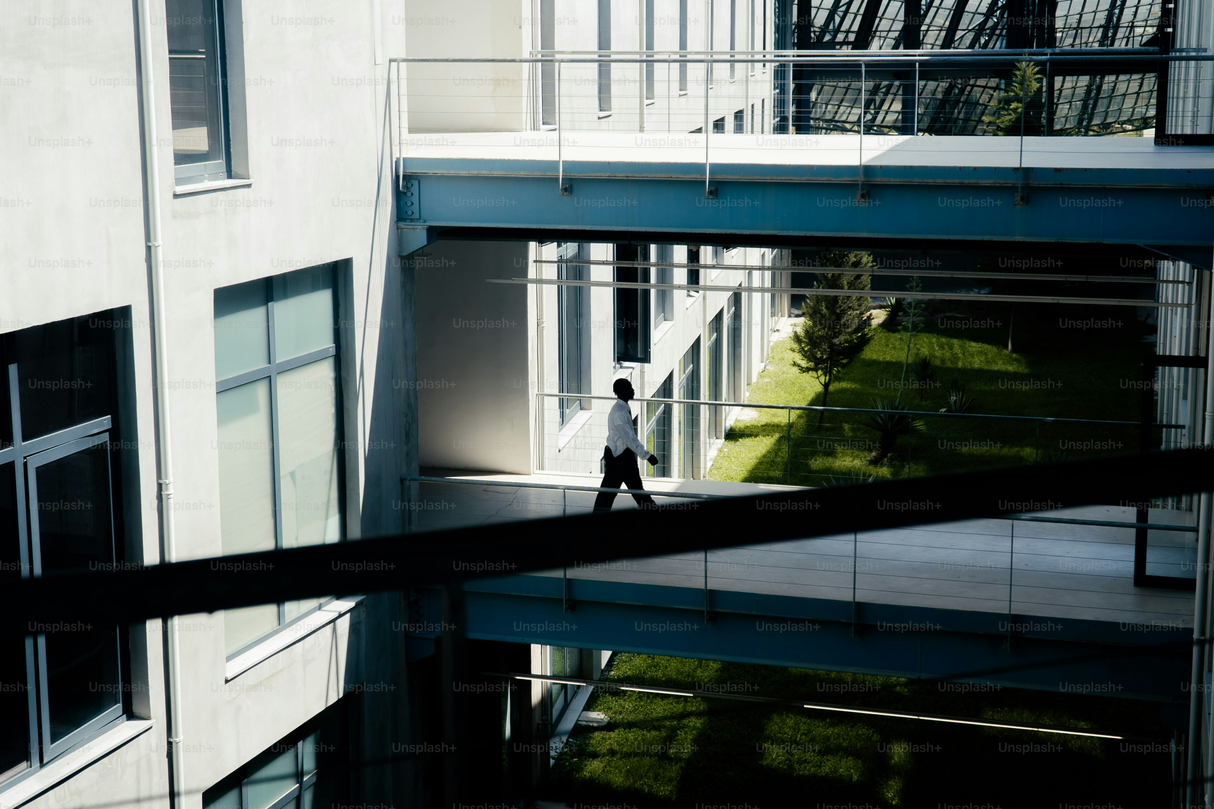 Person, die auf dem erhöhten Gehweg des modernen Gebäudes entlanggeht