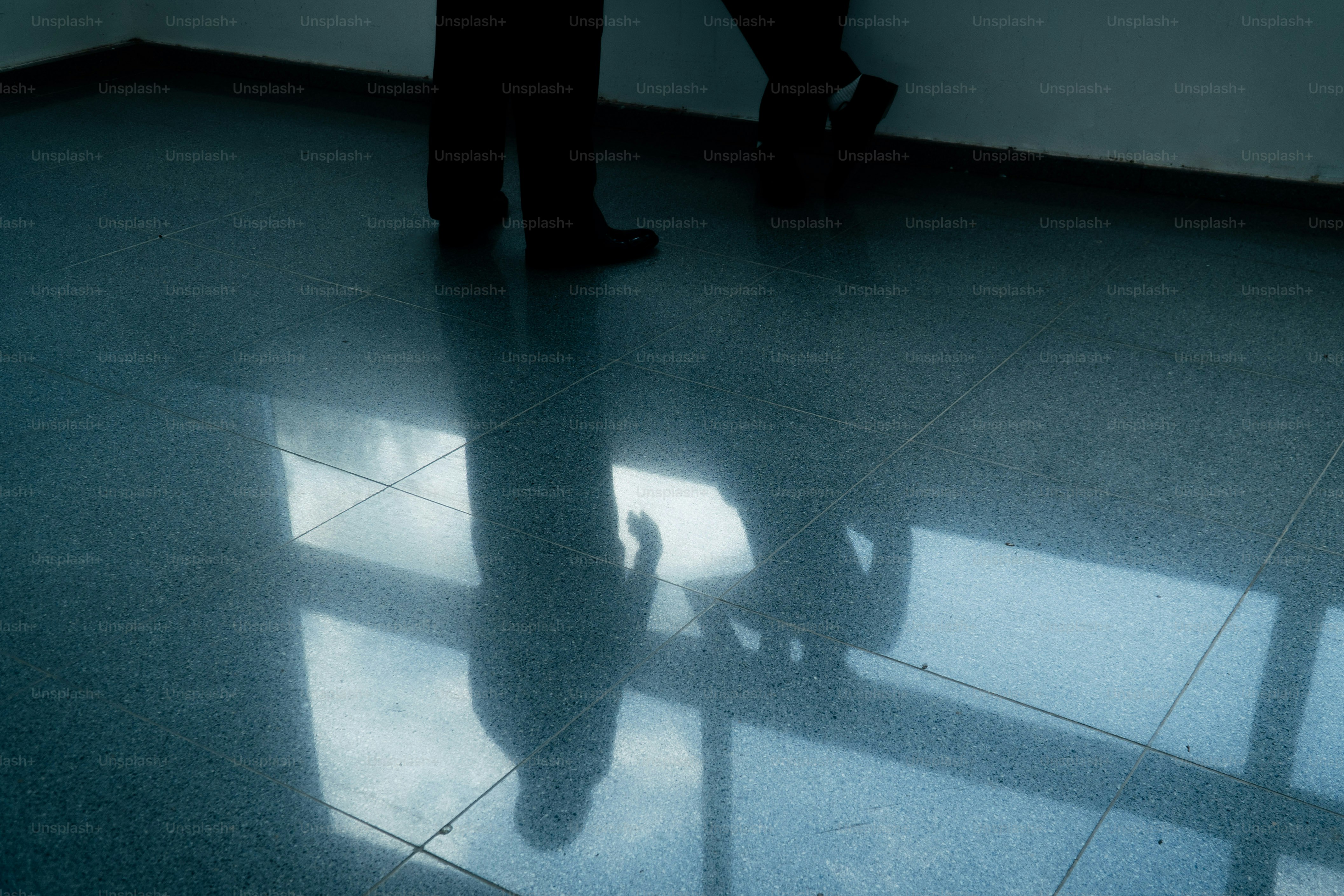 Spiegelungen von Beinen auf glänzendem gefliestem Boden