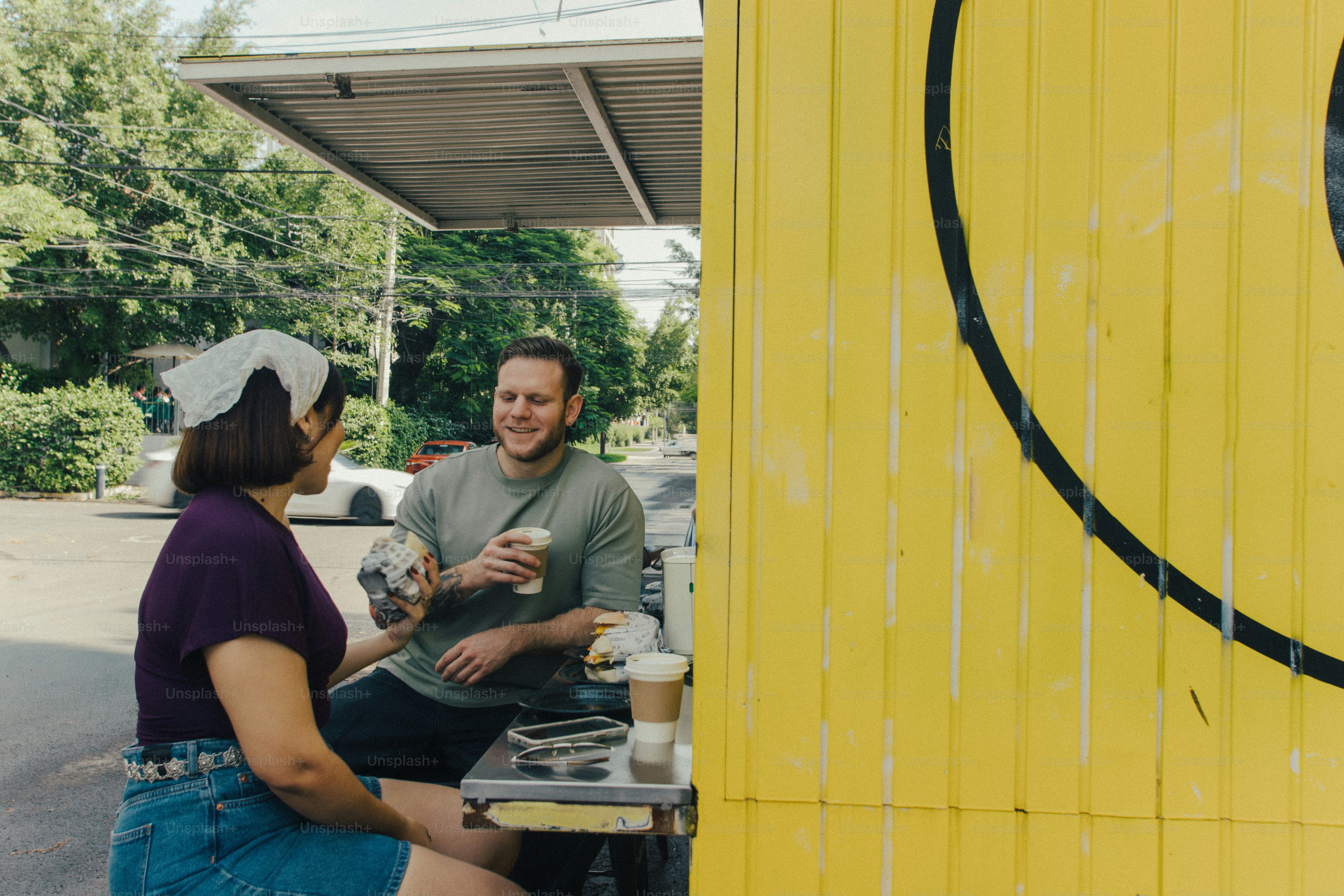 People enjoying coffee outdoors with a yellow smiley wall